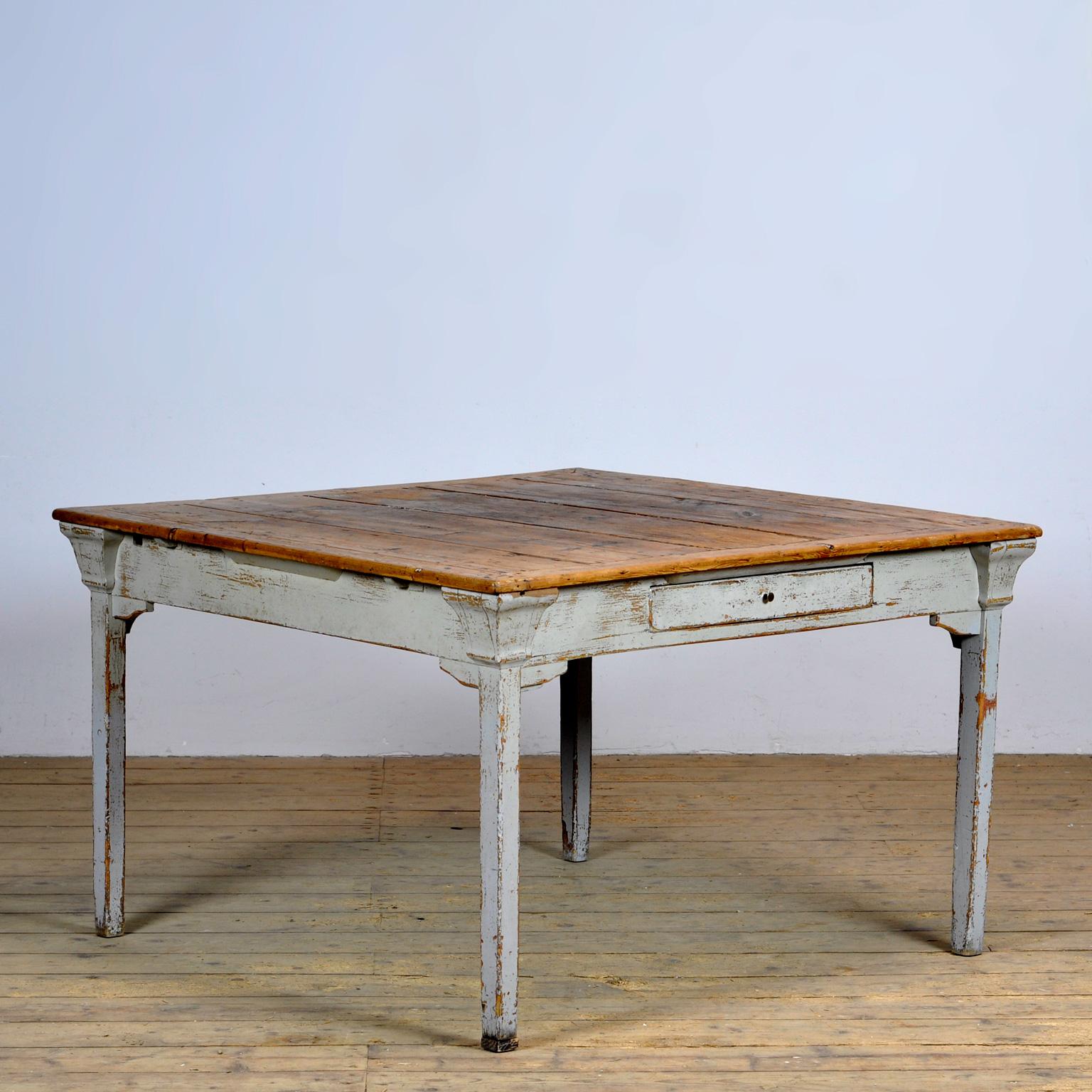 Quadratischer Kiefernholztisch aus einem französischen Kloster. Mit einem lackierten Sockel und einer Platte mit einer schönen Patina, die durch jahrelangen intensiven Gebrauch entstanden ist. Der Tisch hat eine Schublade.

Für Versandpreise fordern