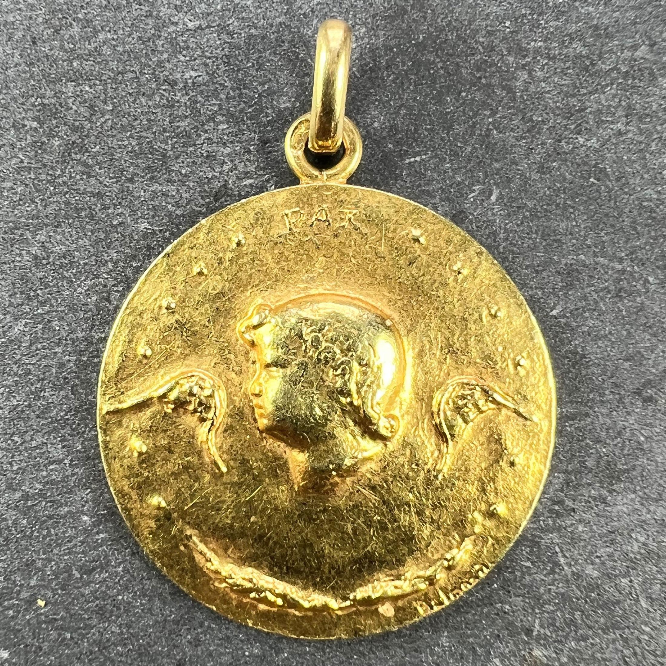 An 18 karat (18K) yellow gold pendant designed as a round medal with an angel or cherub to the centre with wings outspread, an olive branch below and the word PAX above. The whole to symbolise the Angel of Peace. Engraved 'Nathalie' to the reverse