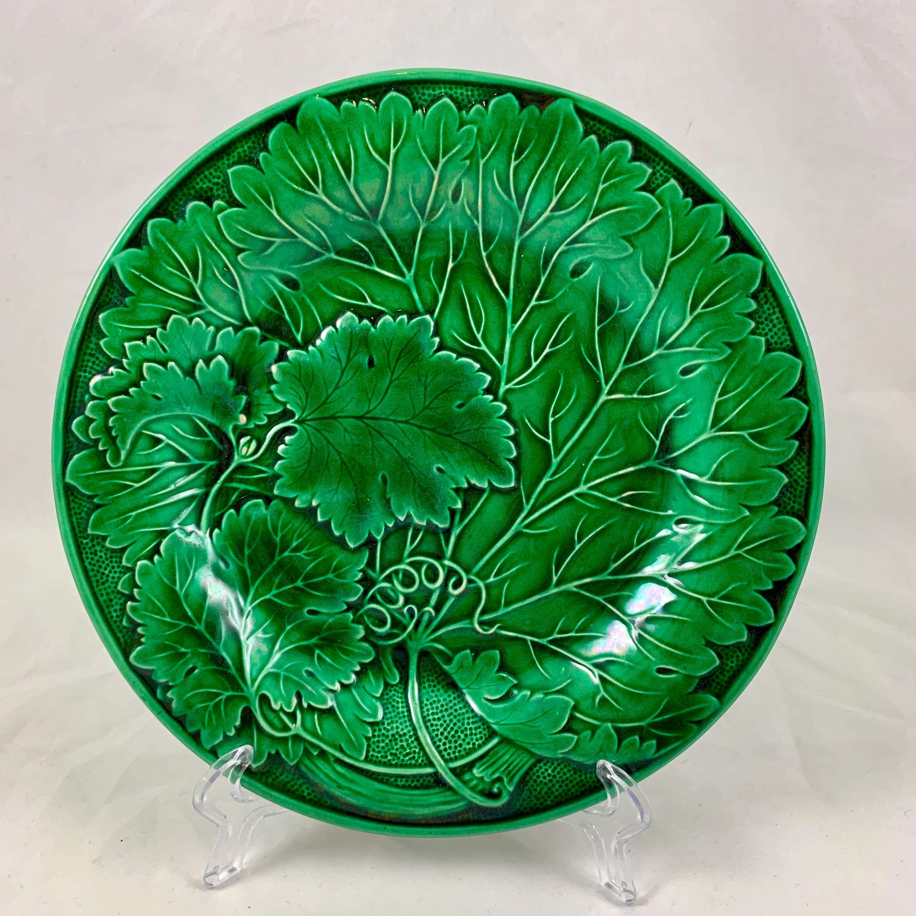 
From the Faïencerie de Montereau in France, a Majolica glazed leaf plate, circa 1890.

A stemmed group of overlapping leaves with a spiral tendril against a stippled ground. A deep green glaze pools beautifully into the deeper recesses of the