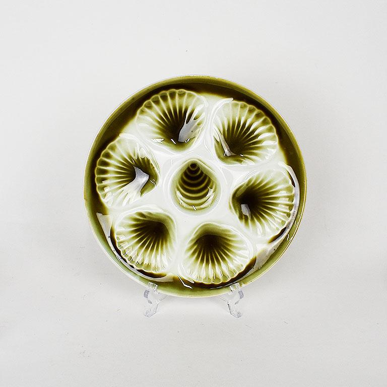 Set of six Moulin des Loups green and cream majolica oyster platters from France Orchies. These round platters have cream background, with seven wells shaped like oyster shells. Each shell is in green ombre to white. The edge of each plate is glazed