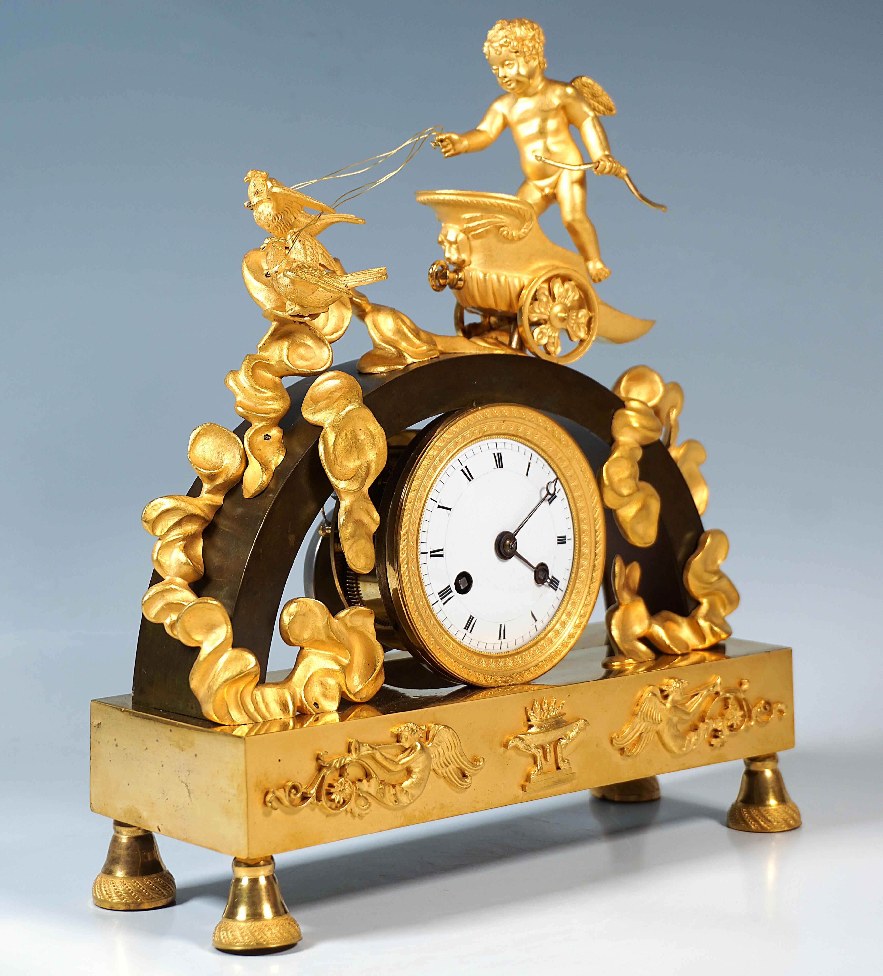 Exquisite mantel clock made of fire-gilded and patinated bronze from the early 19th century:
Structure in the form of a rectangular gilded base on four conical feet with chiselling, relief ornaments applied to the front of the base with trombone