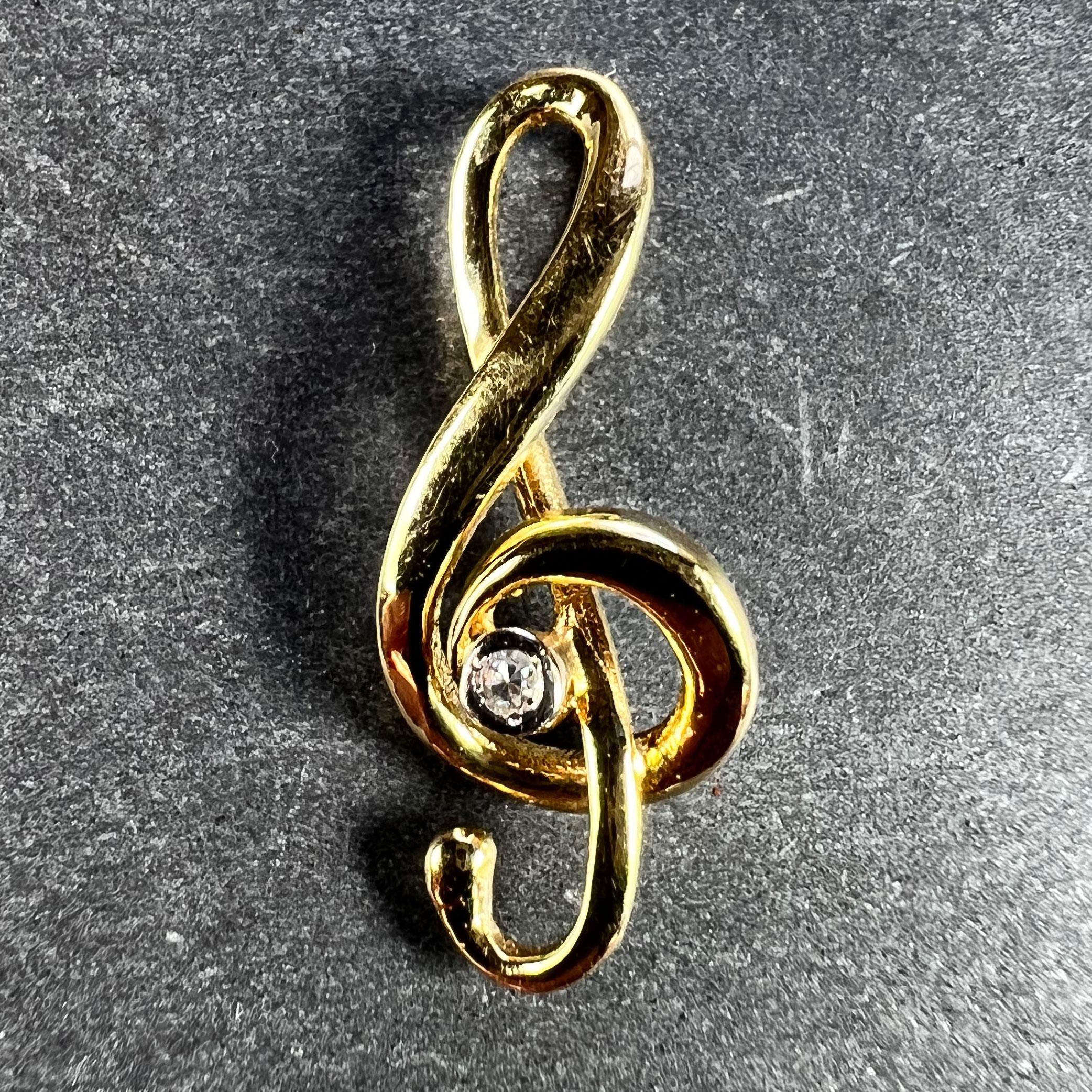 An 18 karat (18K) yellow gold charm pendant designed as the musical note of the treble clef, set to the centre with a single-cut round diamond weighing approximately 0.03 carats. Stamped with the eagle mark for 18 karat gold and French