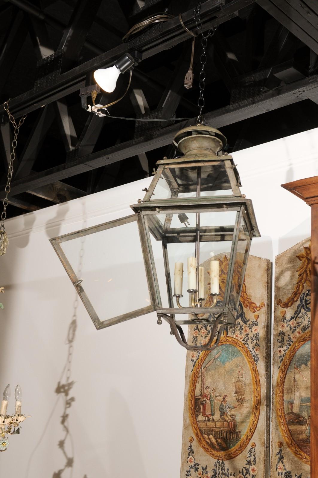 A French Napoléon III period tôle lantern from the mid 20th century, with four lights, original paint and glass panels. Created in France during the reign of Emperor Napoléon III, this tôle lantern features tapering glass panels securing four lights