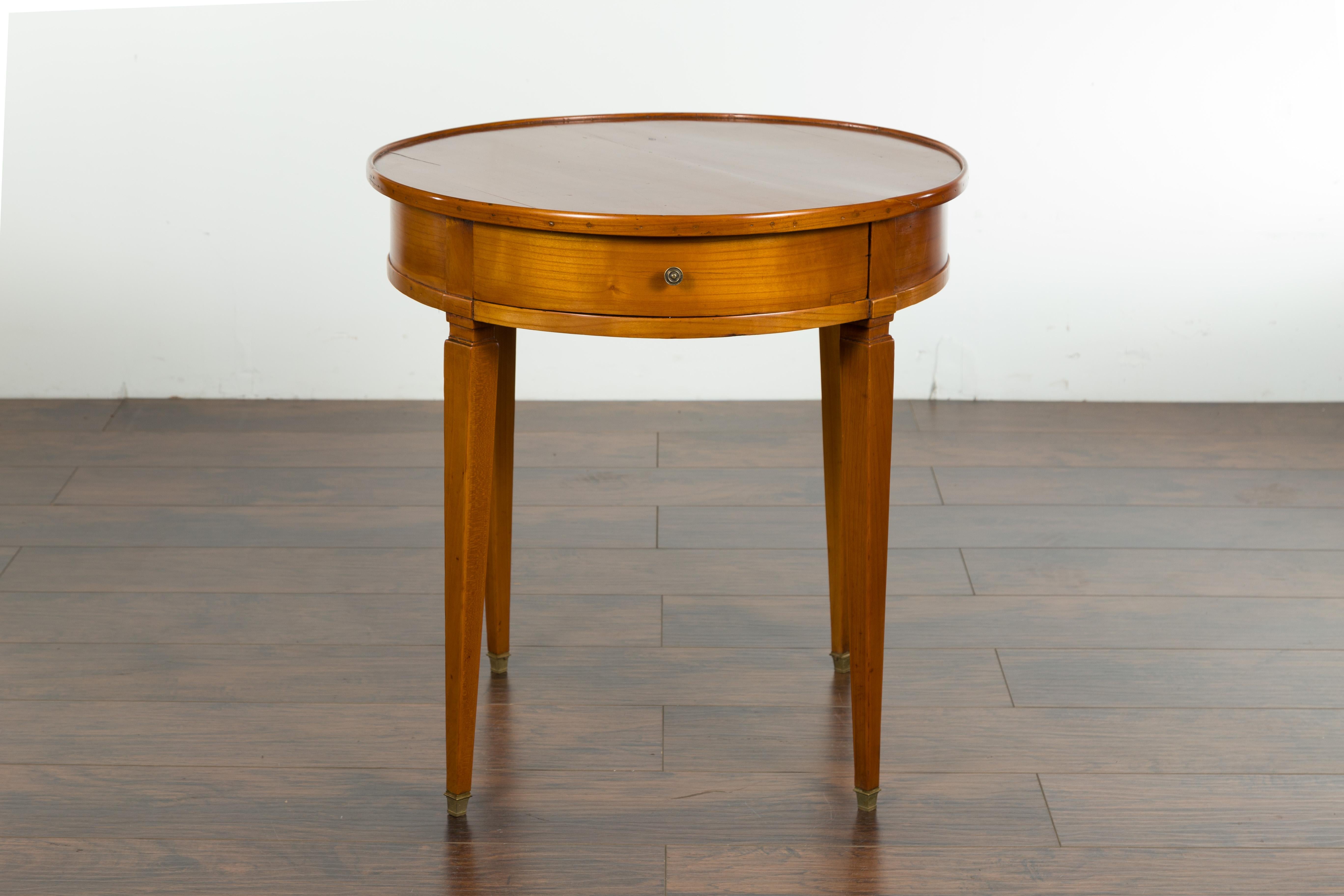 A French Napoléon III period walnut side table from the mid-19th century, with single drawer, tapered legs and brass feet. Created in France at the beginning of Emperor Napoléon III's reign, this walnut side table features a circular top sitting