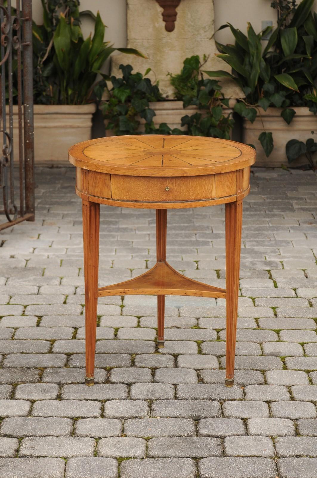 A French Napoleon III walnut guéridon side table from the mid-19th century, with radiating veneer, single drawer and lower shelf. Born in France during the Second Empire, this exquisite guéridon table features a circular top, adorned with radiating