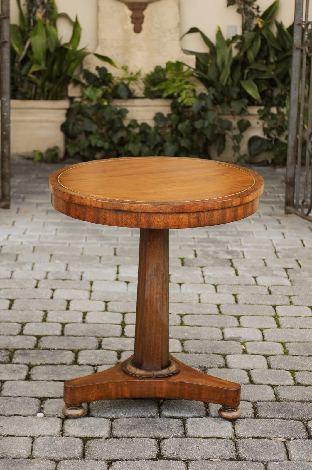 A French Second Empire period walnut guéridon side table from the mid-19th century, with circular top, tripod base and brass inlay. Born in France during the reign of France's last Emperor Napoleon III, this exquisite guéridon pedestal table
