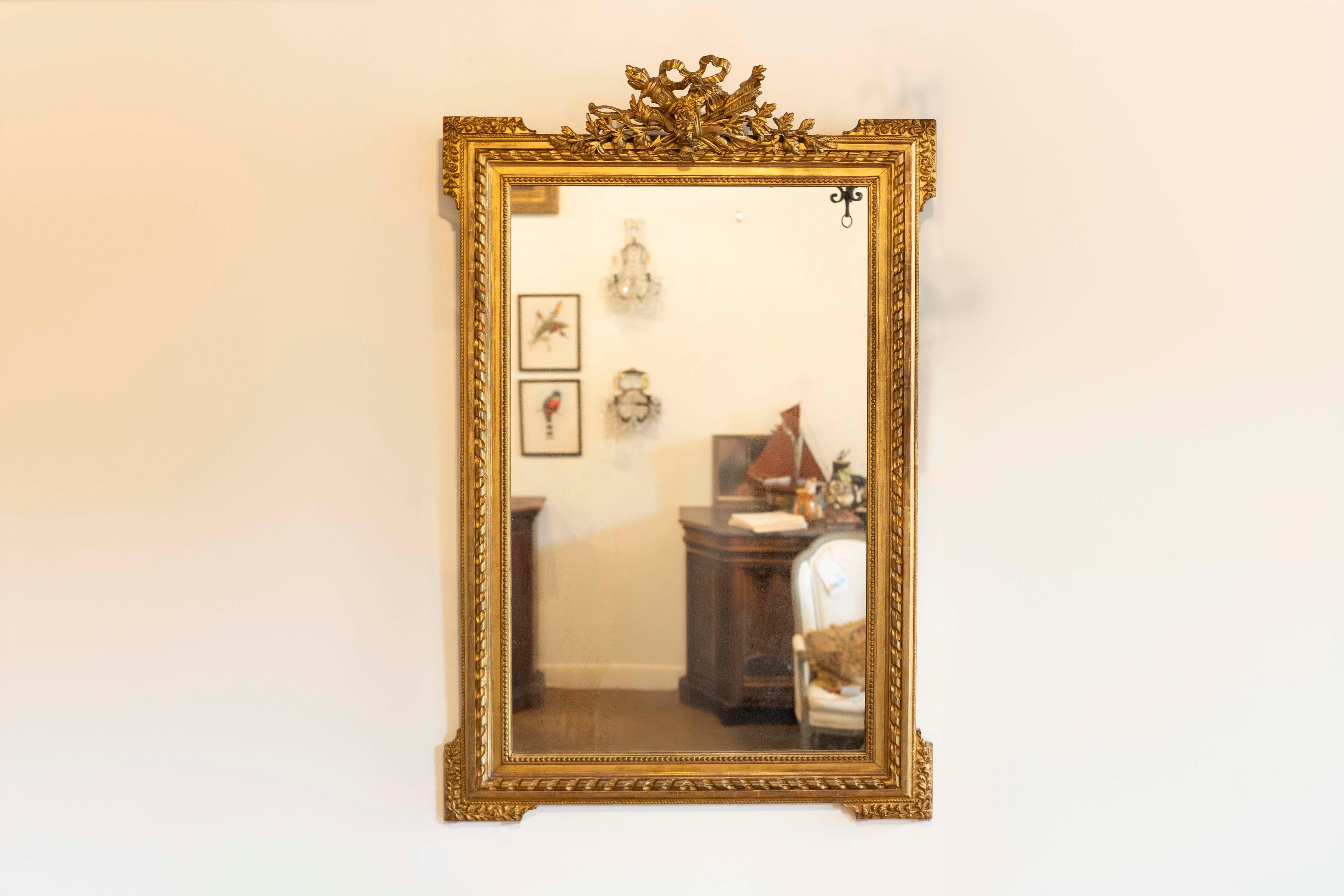 Specchio francese in legno dorato del periodo Napoléon III della fine del XIX secolo, con stemma intagliato raffigurante un trofeo di caccia, nastri intrecciati e piccole perline. Creato in Francia durante il terzo quarto del XIX secolo, questo