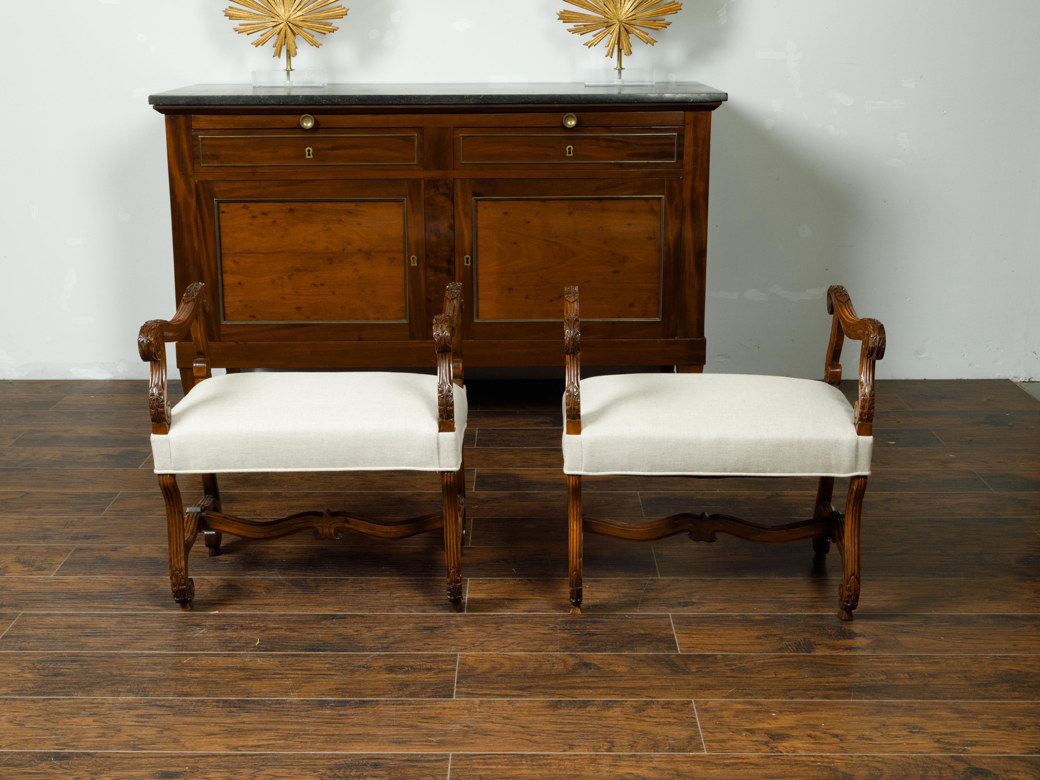 A pair of French Napoléon III walnut stools from the late 19th century, with scrolling accents and new upholstery. Created in France at the end of Emperor Napoléon III's reign, each of this pair of stools features a rectangular top reupholstered