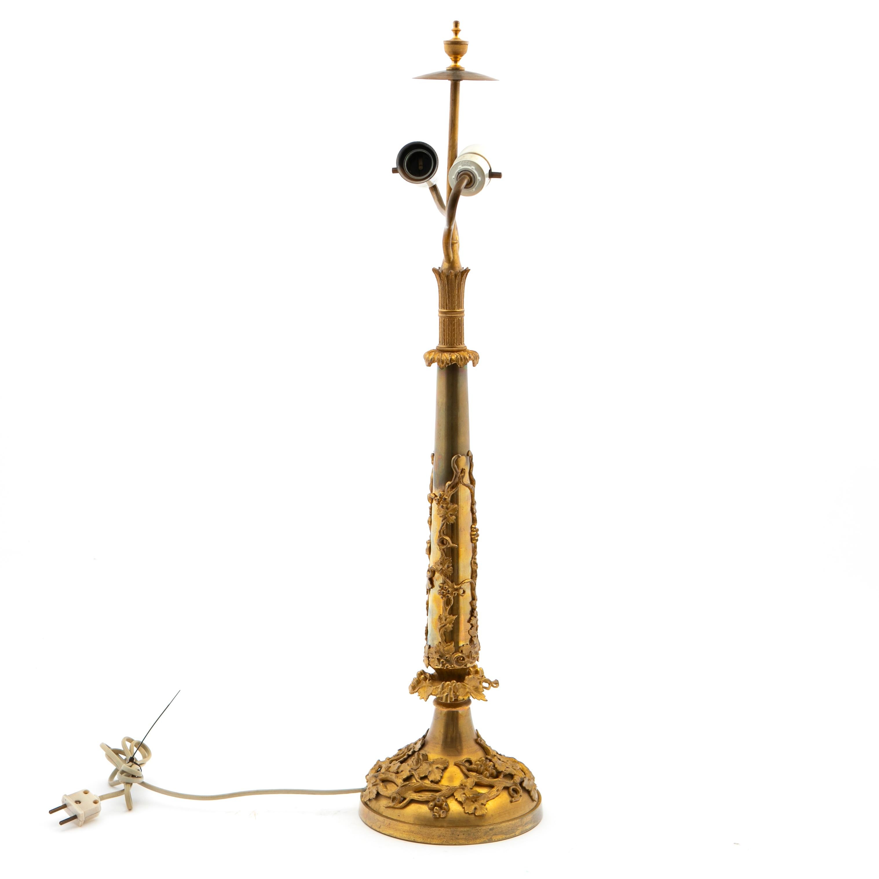 Lampe de table française Napoléon III du XIXe siècle en bronze doré avec deux sources de lumière. Hauteur au sommet : 77 cm.
La base circulaire et le support central conique sont montés avec des raisins et des détails feuillagés en bronze doré. Le