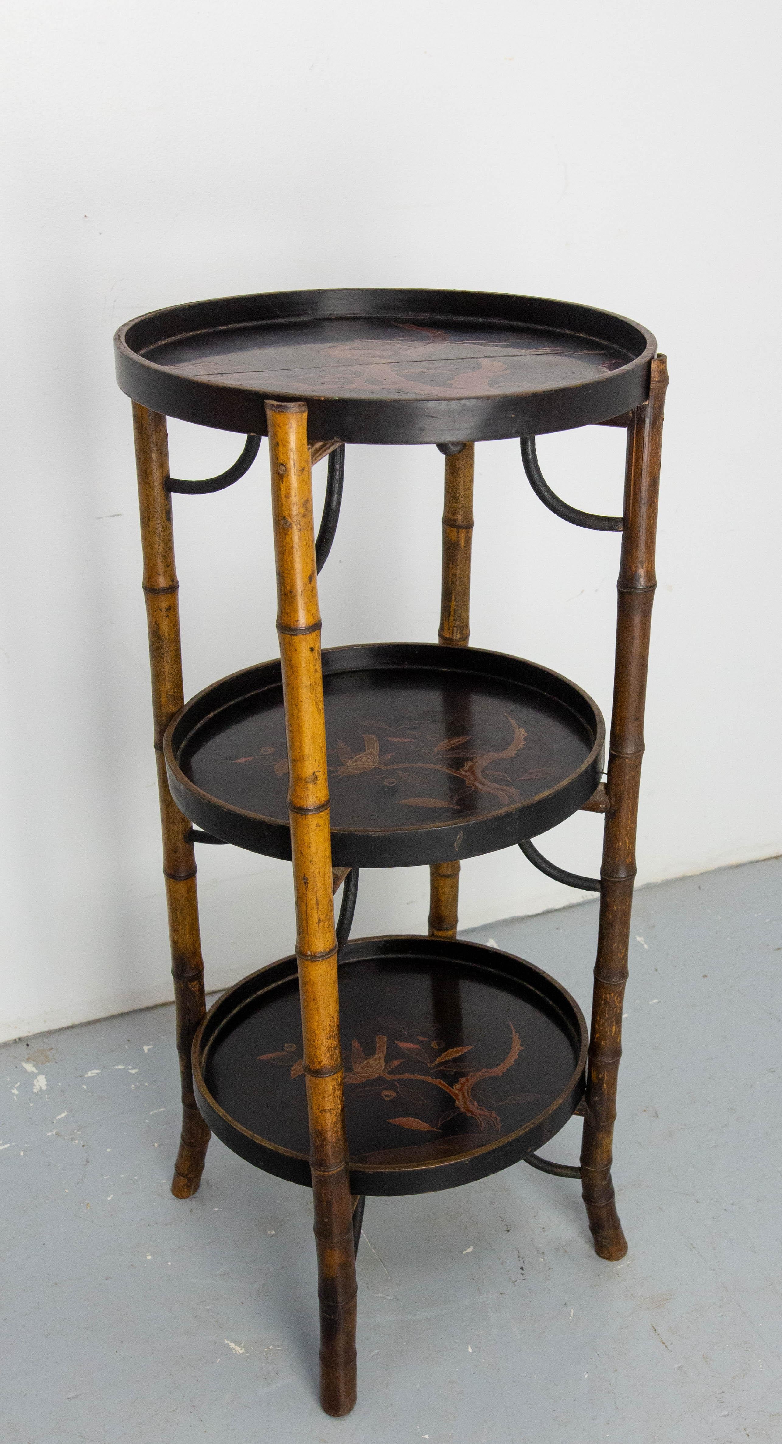 This side table or sellette was made in the late 19th century.
This chinese style sellette is typical of the Napoléon III périod. The entire frame is made of bamboo. 
Each tray is lacquered and depicts a bird on a branch.
The top tray has been split