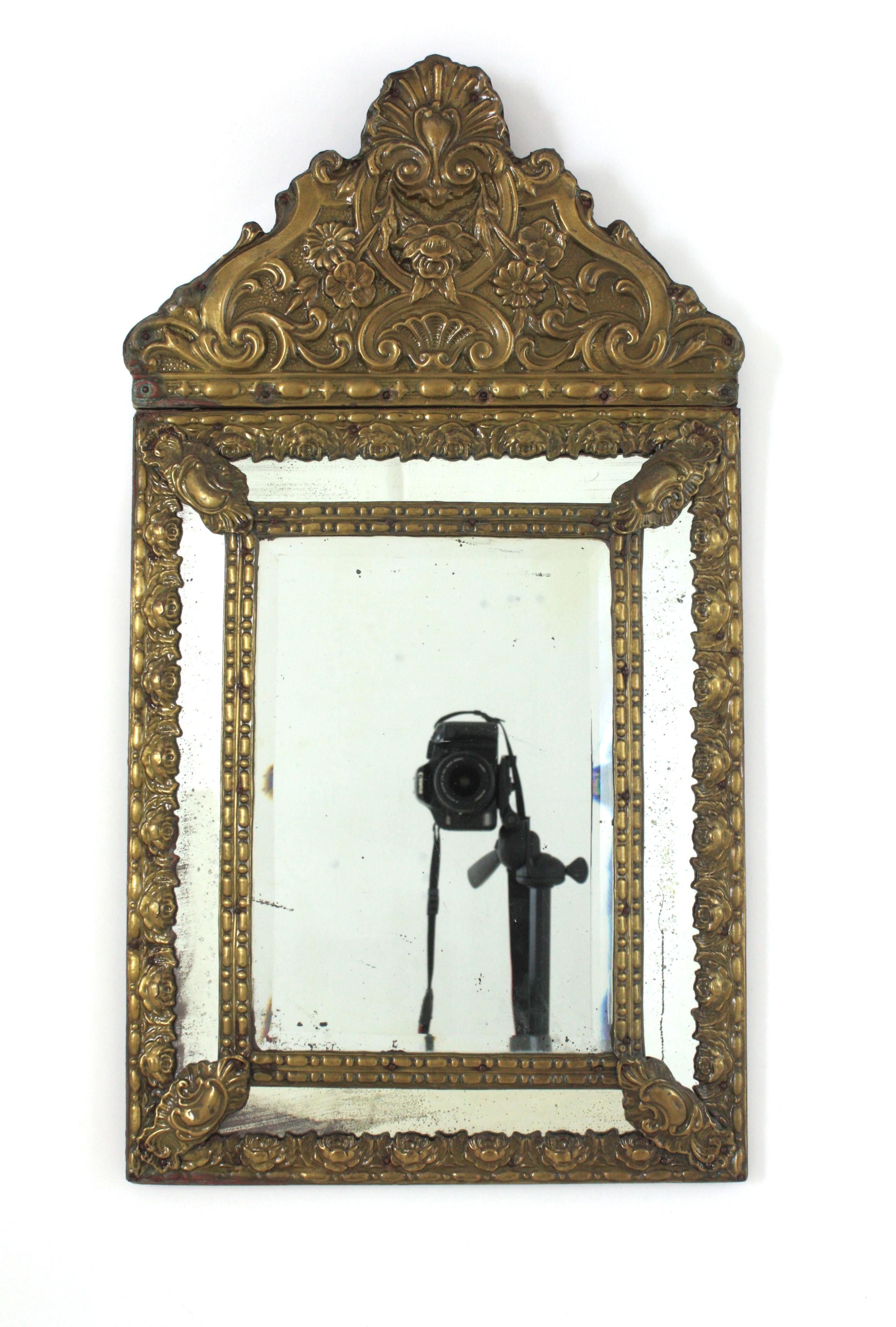 An elegant Napoleon III mirror made with central beveled glass and four rectangular glasses joined between them by decorative brass repousse floral foliage patterns, an elegant filigree repousse brass crest and sculptural foliage details adorning