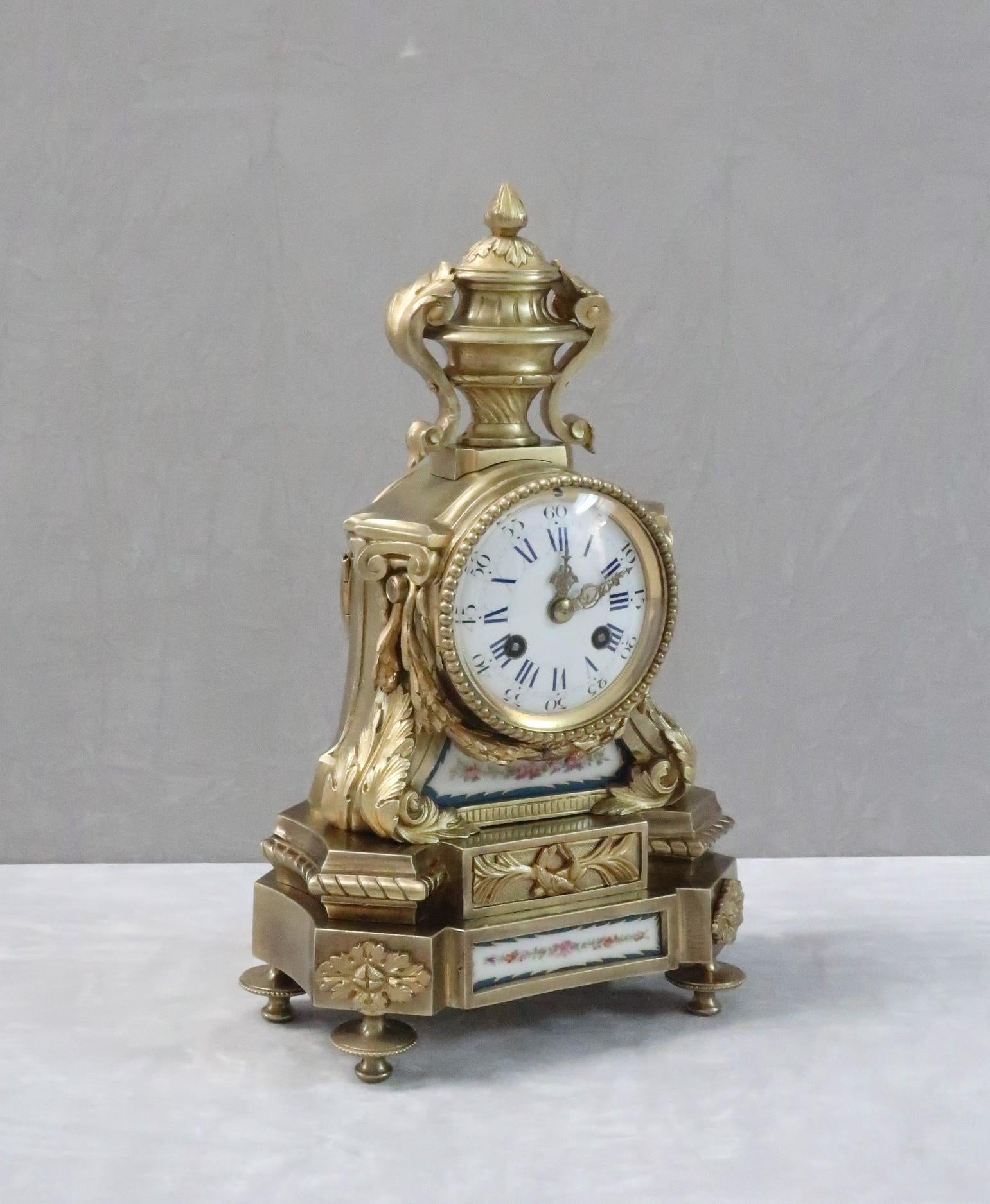 A very good quality French Napoleon III bronze gilt mantel clock with decorative leaf design, swags, beaded detail and urn to the top with inset hand painted floral Sevres style porcelain panels within a blue border. The clock has a French eight day