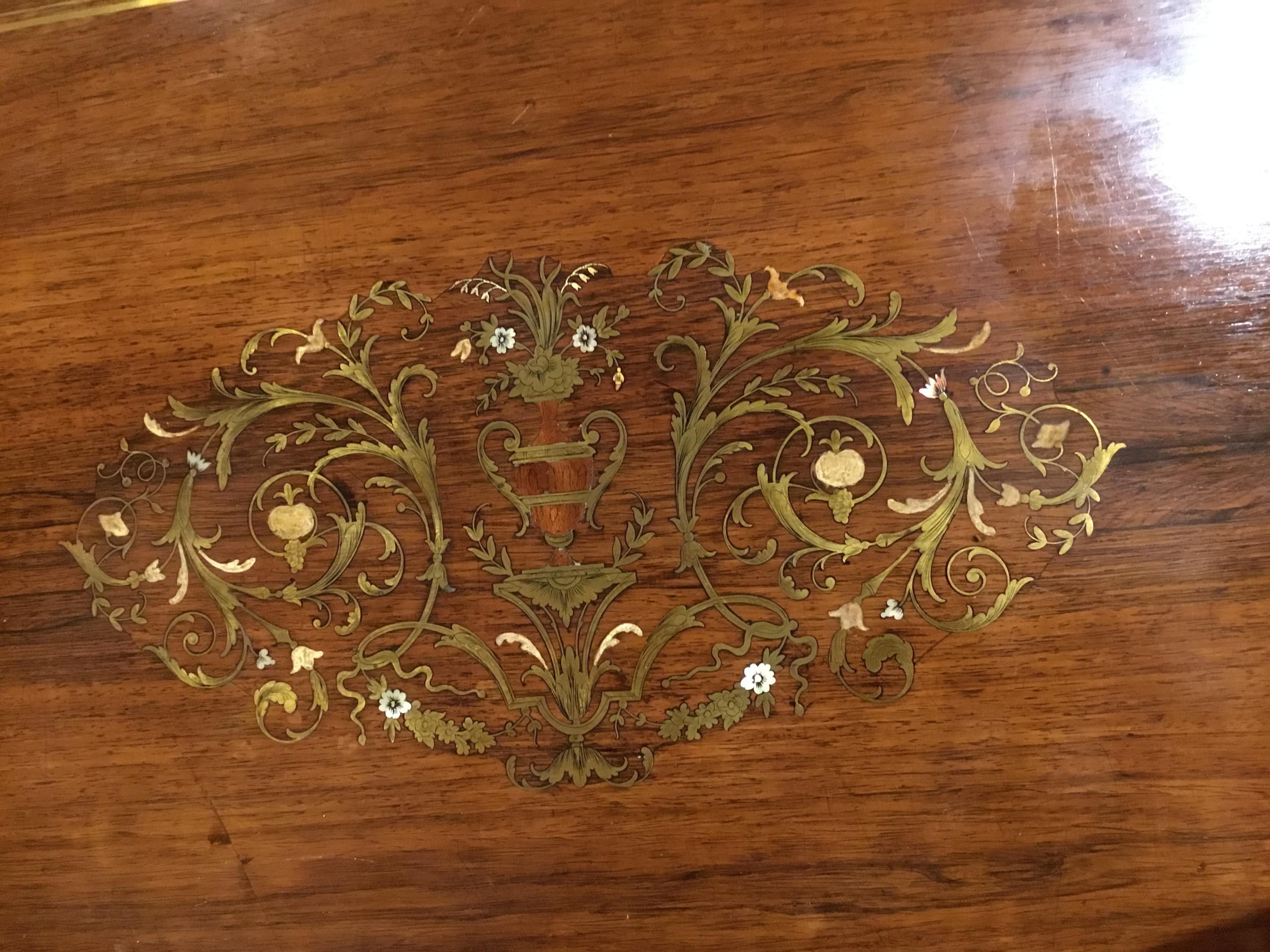 Rosewood oval center table with brass inlay designs with touches of mother of pearl.
Gilt bronze mounts on the gadrooned edge with gilt bronze flutes. Superb patina and color
The oval top resting on tapered legs held by a contoured stretcher.