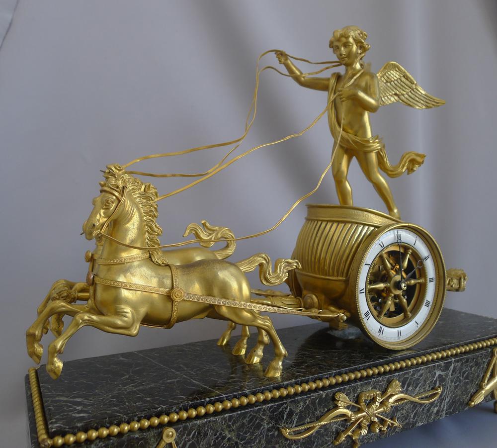 Une bonne pendule française d'époque Napoléon III en marbre vert antique et bronze doré. Le sujet est un Cupidon chevauchant un beau char tiré par une paire de chevaux vifs et très bien modelés. Les rênes sont toutes entièrement décorées et les