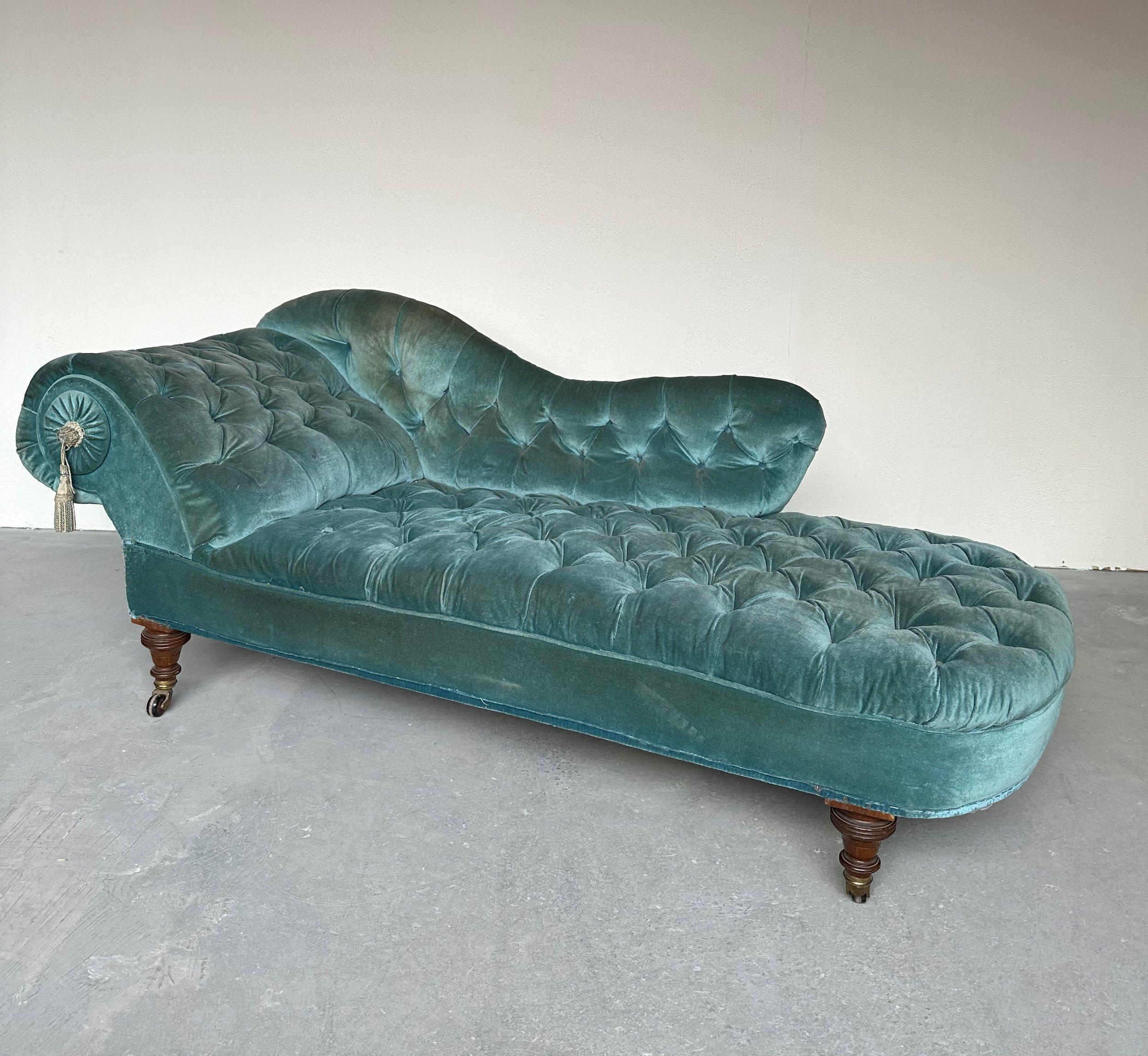 This elegant French 19th century Napoleon III tufted chaise lounge showcases the artistry of the period. It features a gracefully sloped and curved extended left arm, and scrolled back with a decorative tassle accent. The interior of the back and