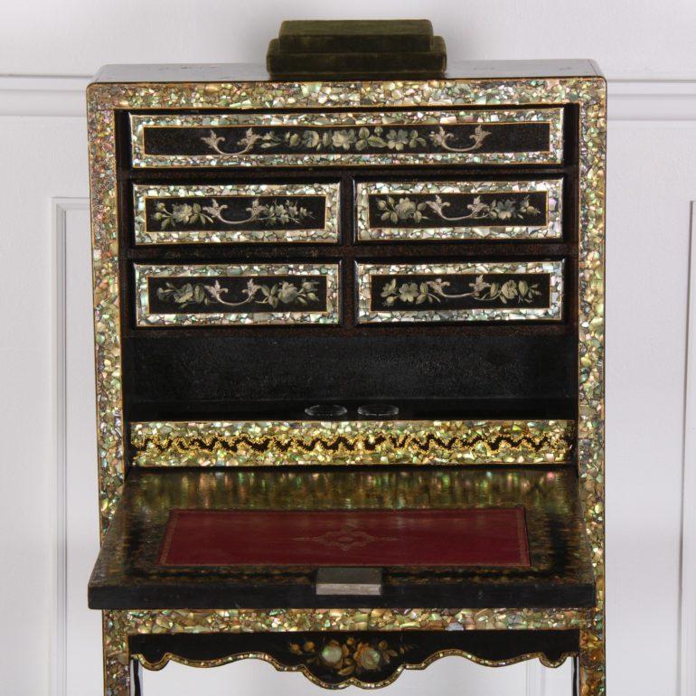 A French, ebonized and mother of pearl-inlaid, drop-front writing desk, the interior with fitted drawers, glass inkwells and a gilt-tooled leather writing surface.

The exterior is profusely inlaid with mother of pearl and further embellished with