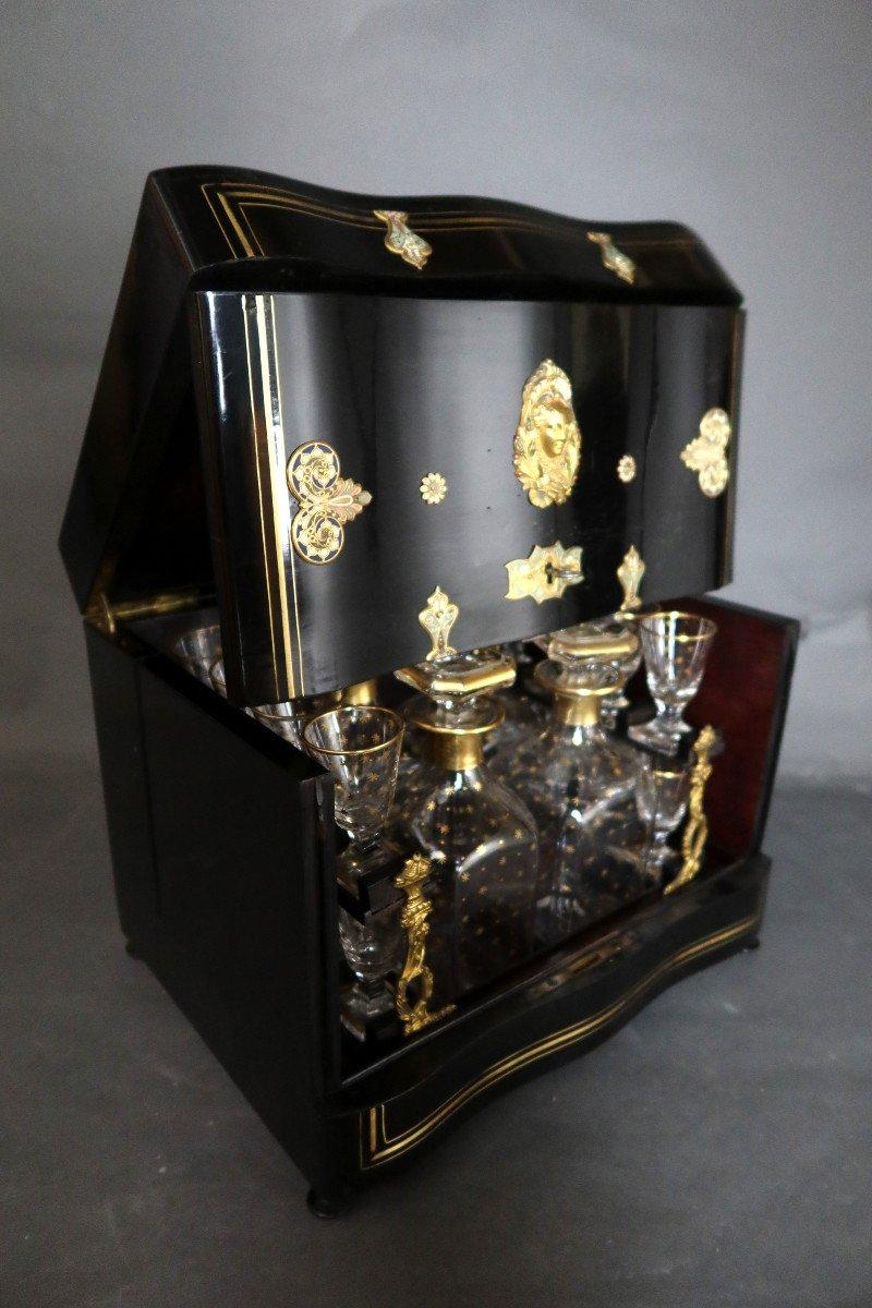 Liquor cellar in blackened wood decorated with gilded bronze and colored enamels, Napoleon III period. 
This cellar contains a basket with four carafes and 16 glasses decorated with gold (one damaged glass glued back together).
Rare model and