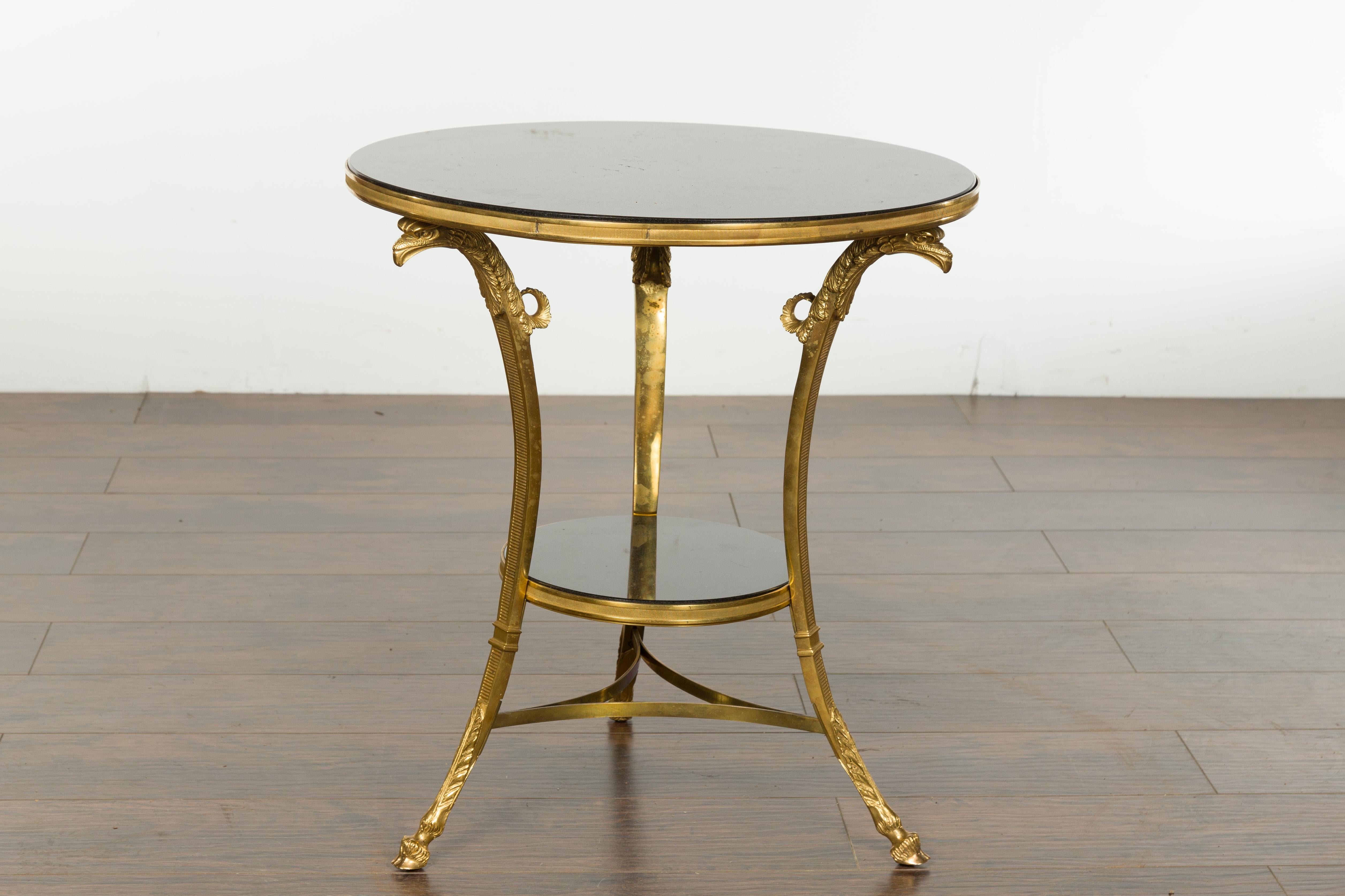 French Napoléon III period gilt bronze table from the mid-19th century, with black marble top and shelf and eagle heads. Created in France during the reign of Emperor Napoléon III's reign, this gilt bronze side table features a circular black marble