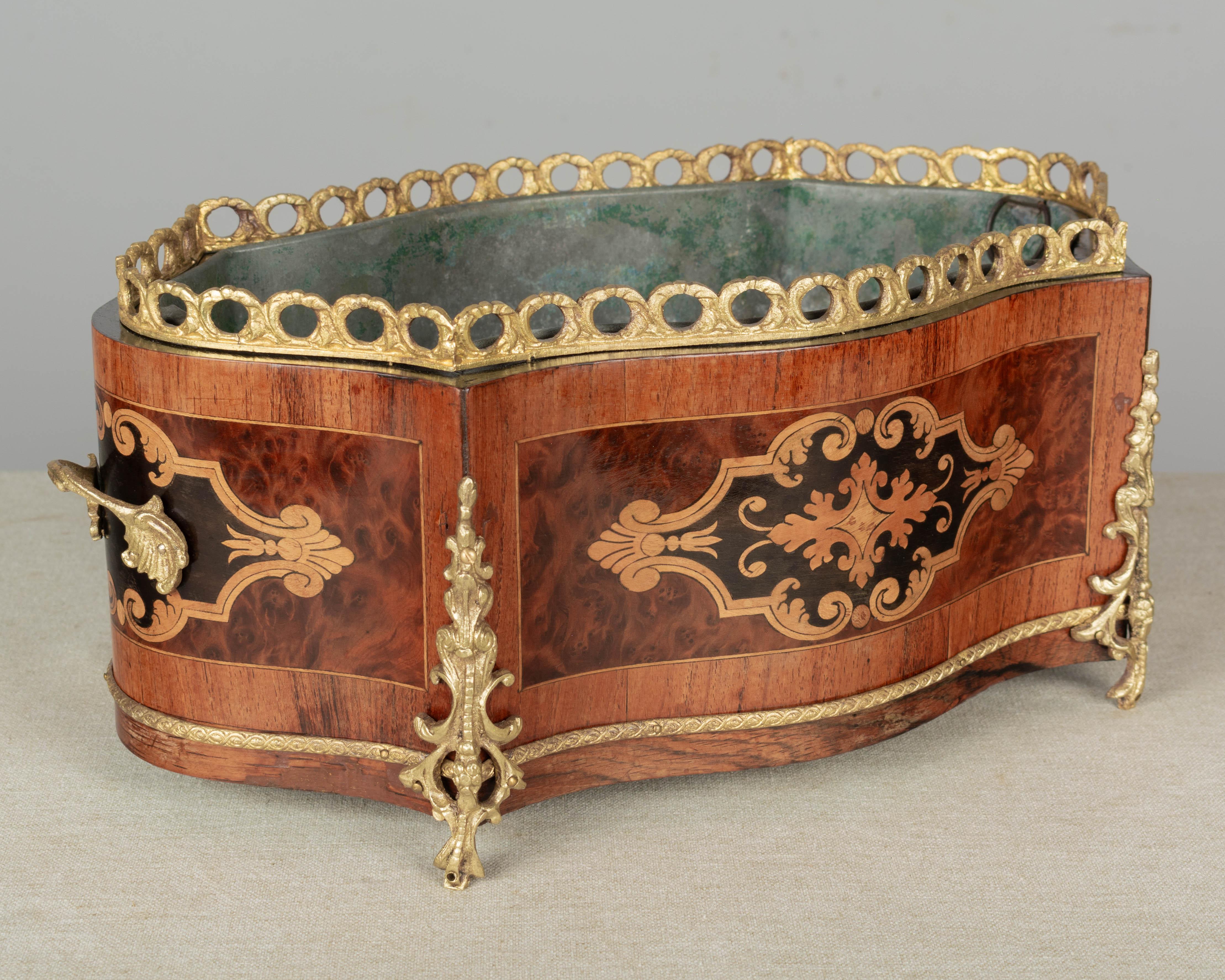 An early 20th century French Napoleon III marquetry jardinière with inlaid veneers of mahogany, burled elm and walnut wood with ebonized trim. Bronze-mounted with two handles, gallery and trim. Original zinc liner, repaired. A beautiful planter for