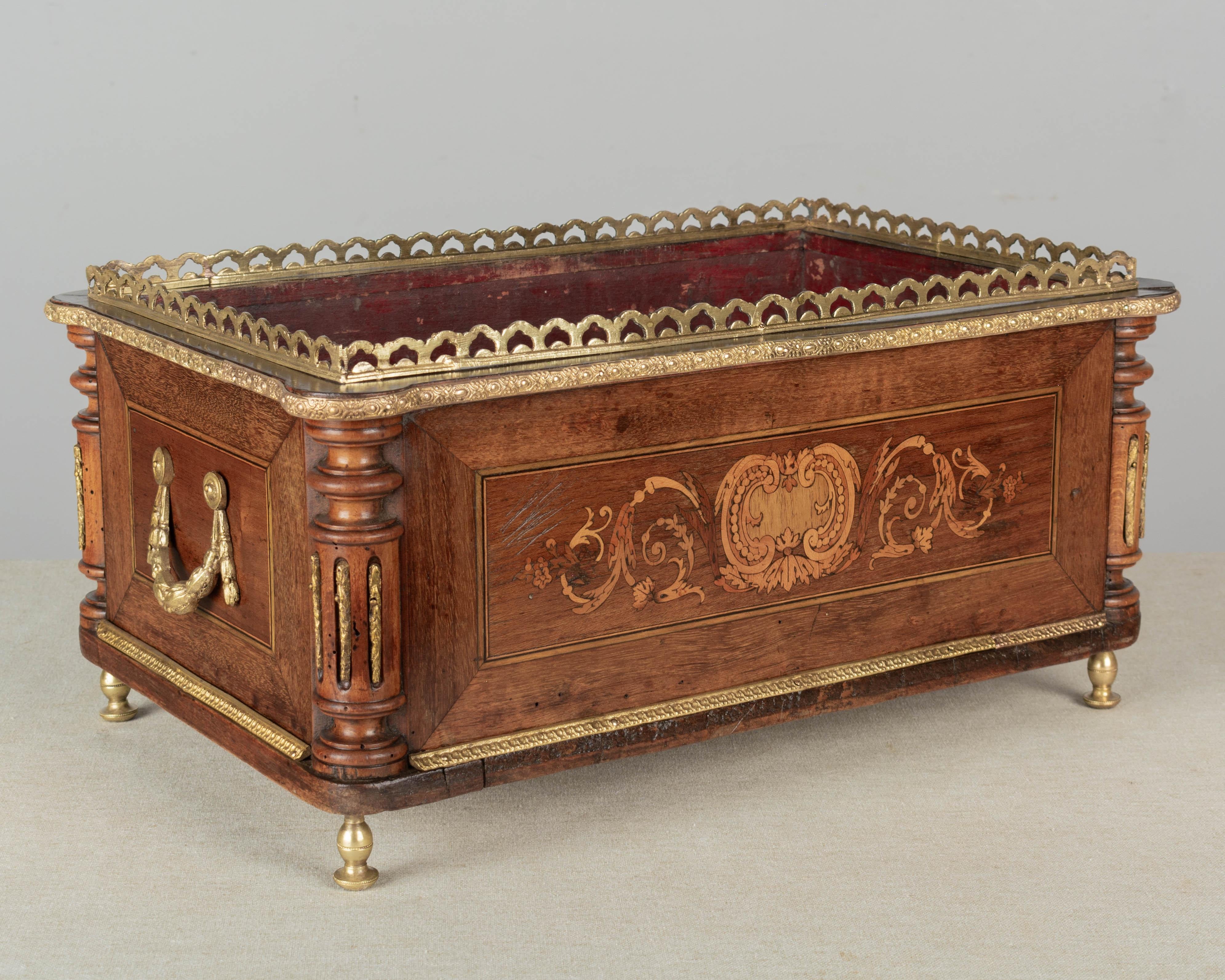 An early 20th century French Napoleon III marquetry jardinière with inlaid veneers of walnut and mahogany and turned corner details. Bronze-mounted with two handles, gallery and trim. Missing the zinc liner. A beautiful planter for the display of