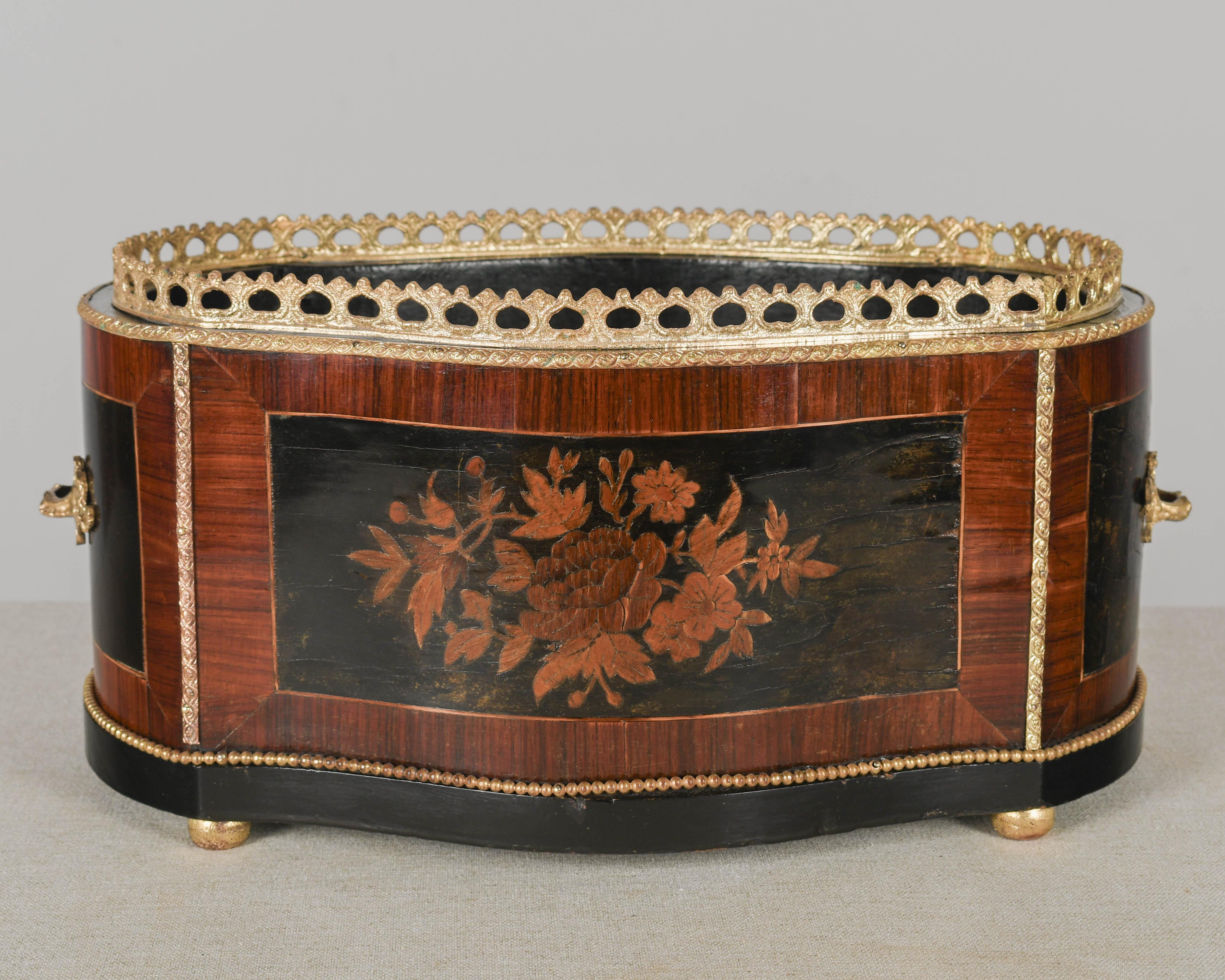 An early 20th century French Napoleon III style marquetry jardinière, or cachepot, with floral decoration made of inlaid veneers of mahogany. Cast bronze handles, gallery and trim. Ebonized interior. Missing the zinc liner. Perfect for the display