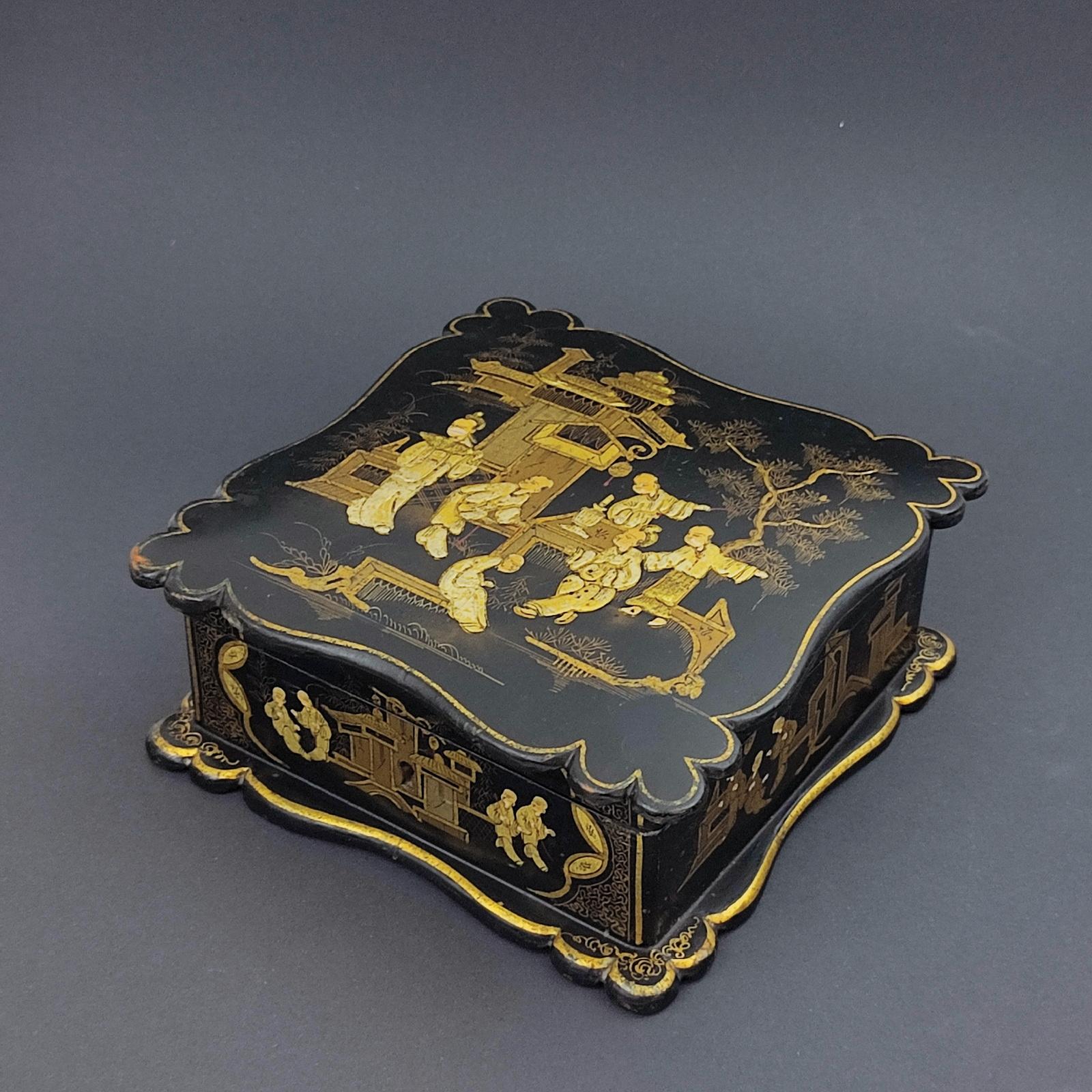 French Napoleon III Jewelry Box in Black Lacquer with Asian Decor, 19th Century.
A square jewelry box with ribbed edges, decorated with gold courtiers in the palace, on a black lacquer background. Interior padded in pink silk.

Napoleon III
