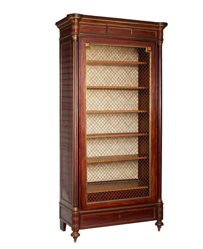 La libreria è impiallacciata in mogano con montaggio e intarsi in ottone ormolu. L'anta in rete di ottone si apre su 6 originali ripiani intarsiati, che possono essere regolati in altezza. Un cassetto alla base.