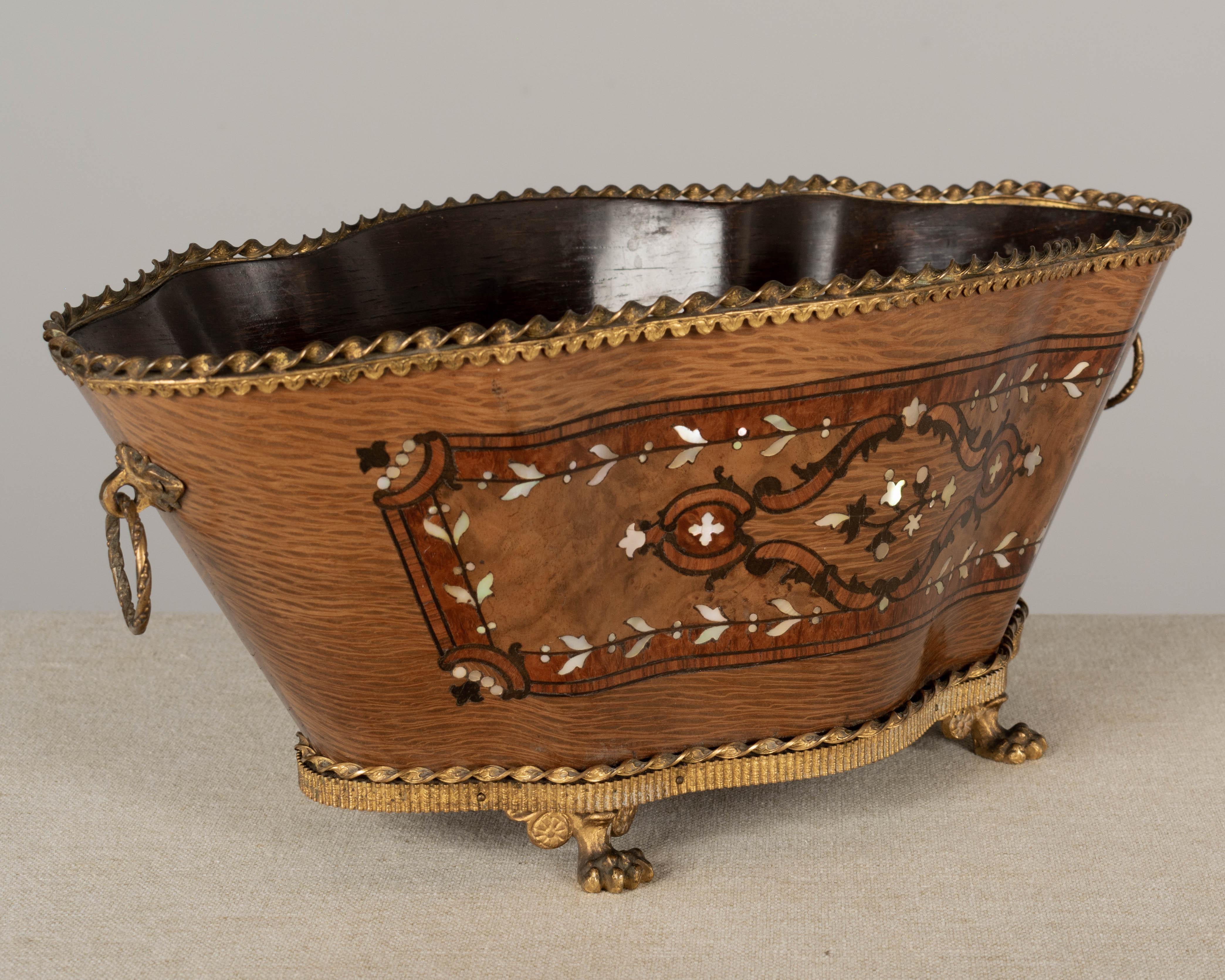 An early 20th century Napoleon III style oval jardinière, or planter, made of rosewood with fine marquetry inlay of various woods and mother of pearl. French polish finish. Bronze-mounted with rig handles and decorative cast lion paw feet. A