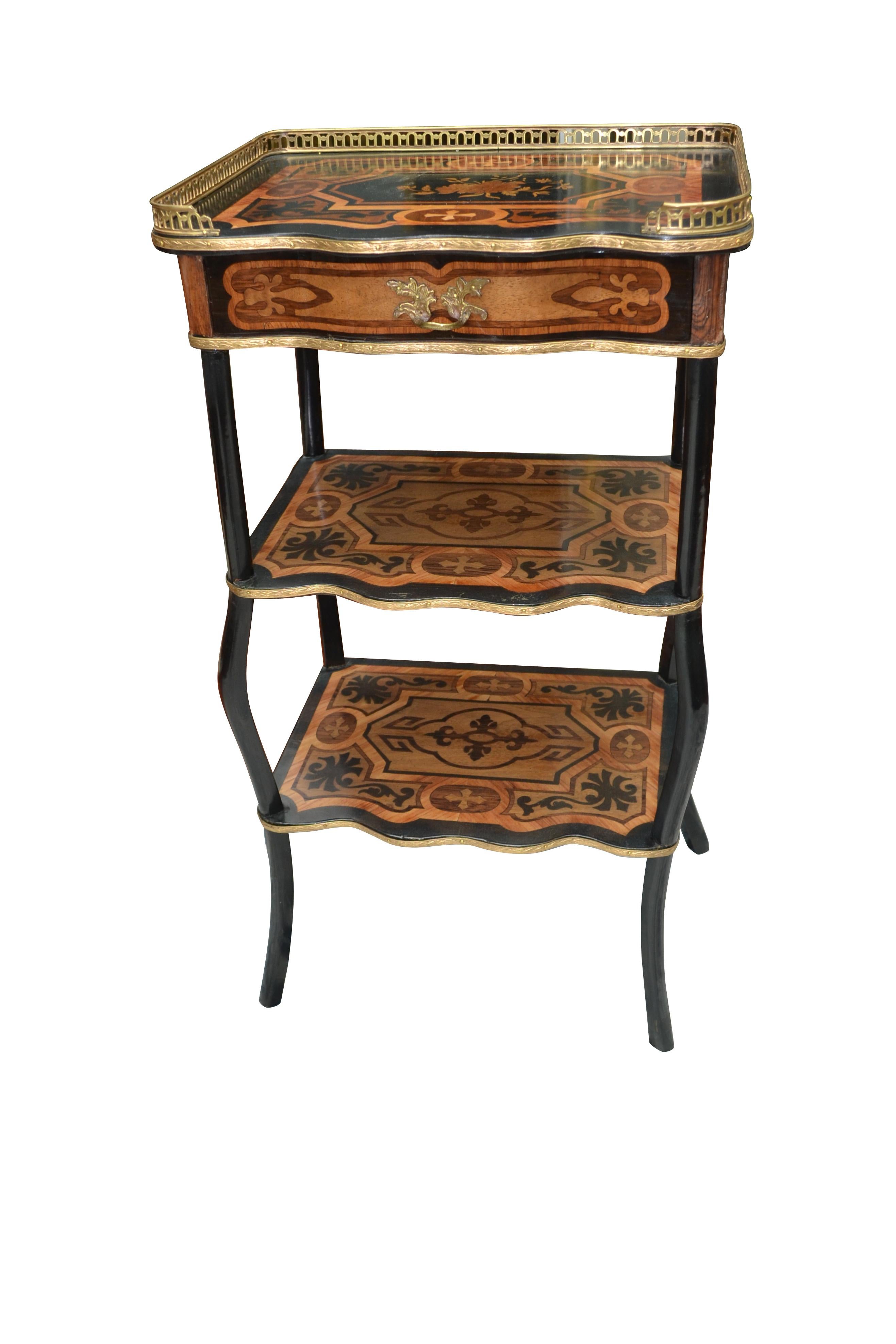 A Napoleon III marquetry side table. The top galleried section with a drawer and the two bottom shelves having overall inlaid exotic wood inlay in a geometric pattern. The top and lower shelves are supported by four curved legs.