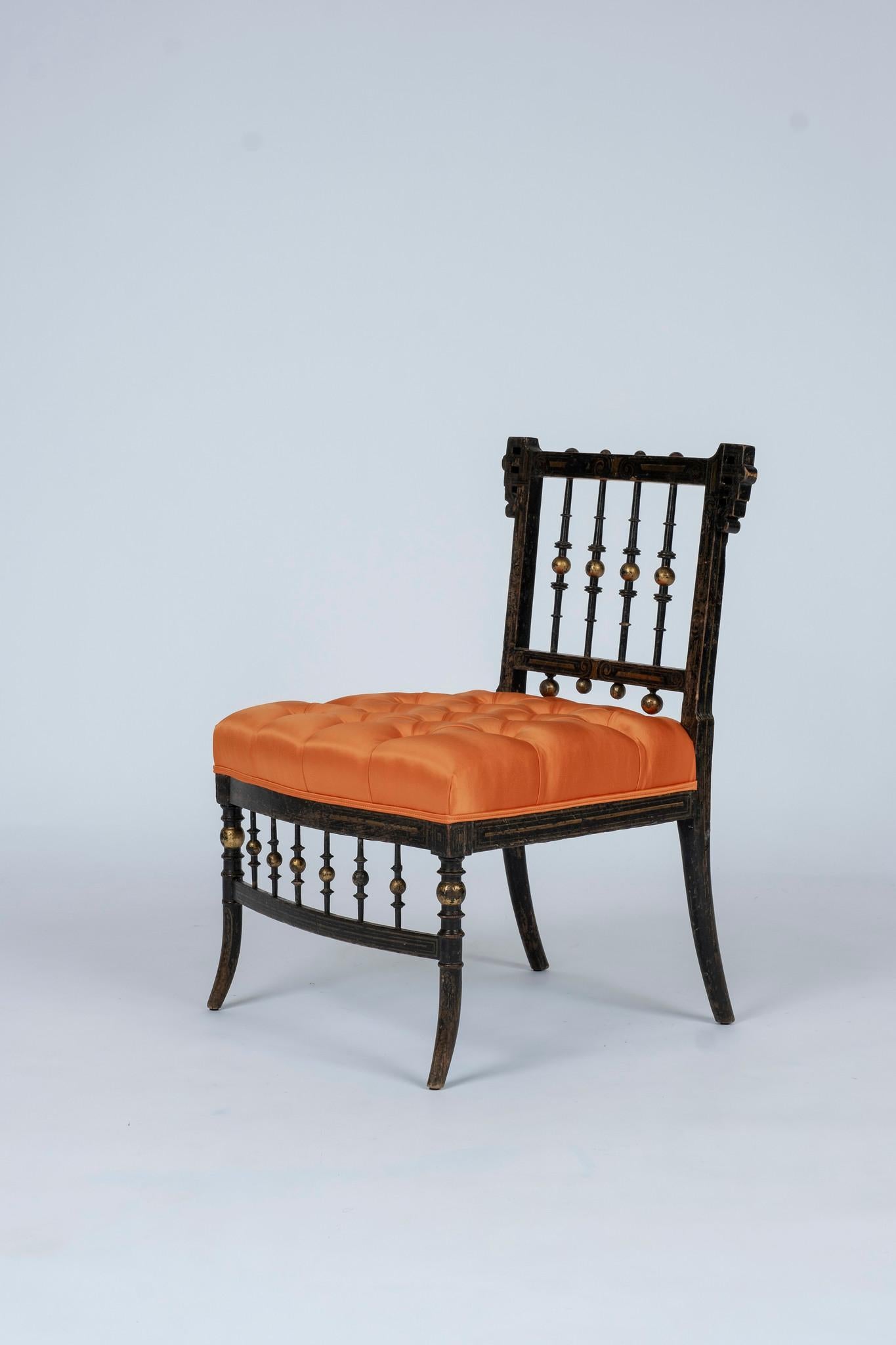 These low chairs were all of the rage in mid-19th century Paris. It's ebonized wood frame has been decorated with polychrome and parcel-gilt details and newly upholstered in a luxurious satin silk with button tufted detailing. A perfect chair to