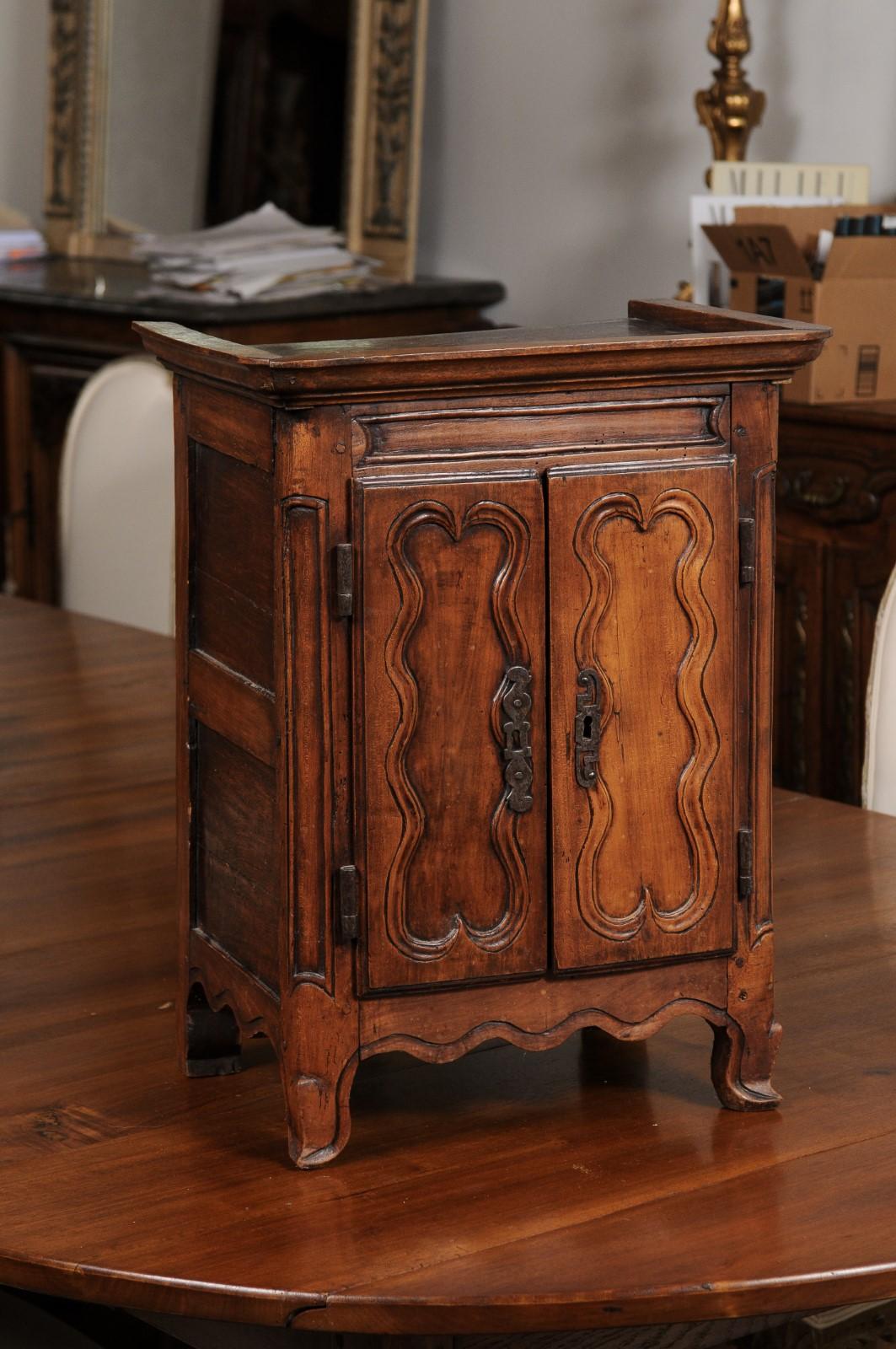 A French Napoléon III period miniature walnut armoire from the mid 19th century, with molded panels and scrolling feet. Created in France at the beginning of Emperor Napoléon III's reign, this miniature walnut armoire will make for a great addition