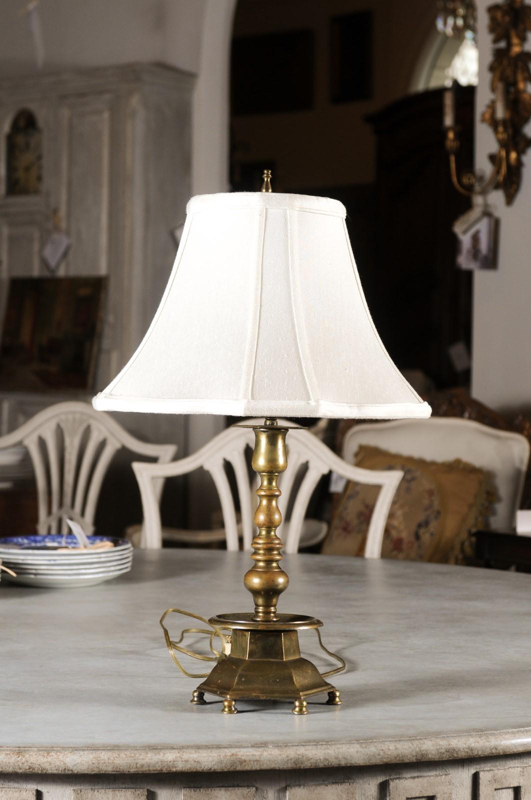 A French Napoléon III period brass candlestick table lamp from the late 19th century, with hexagonal base and newer shade. Created in France at the end of Emperor Napoléon III's reign, this lamp features a brass candlestick resting on an hexagonal