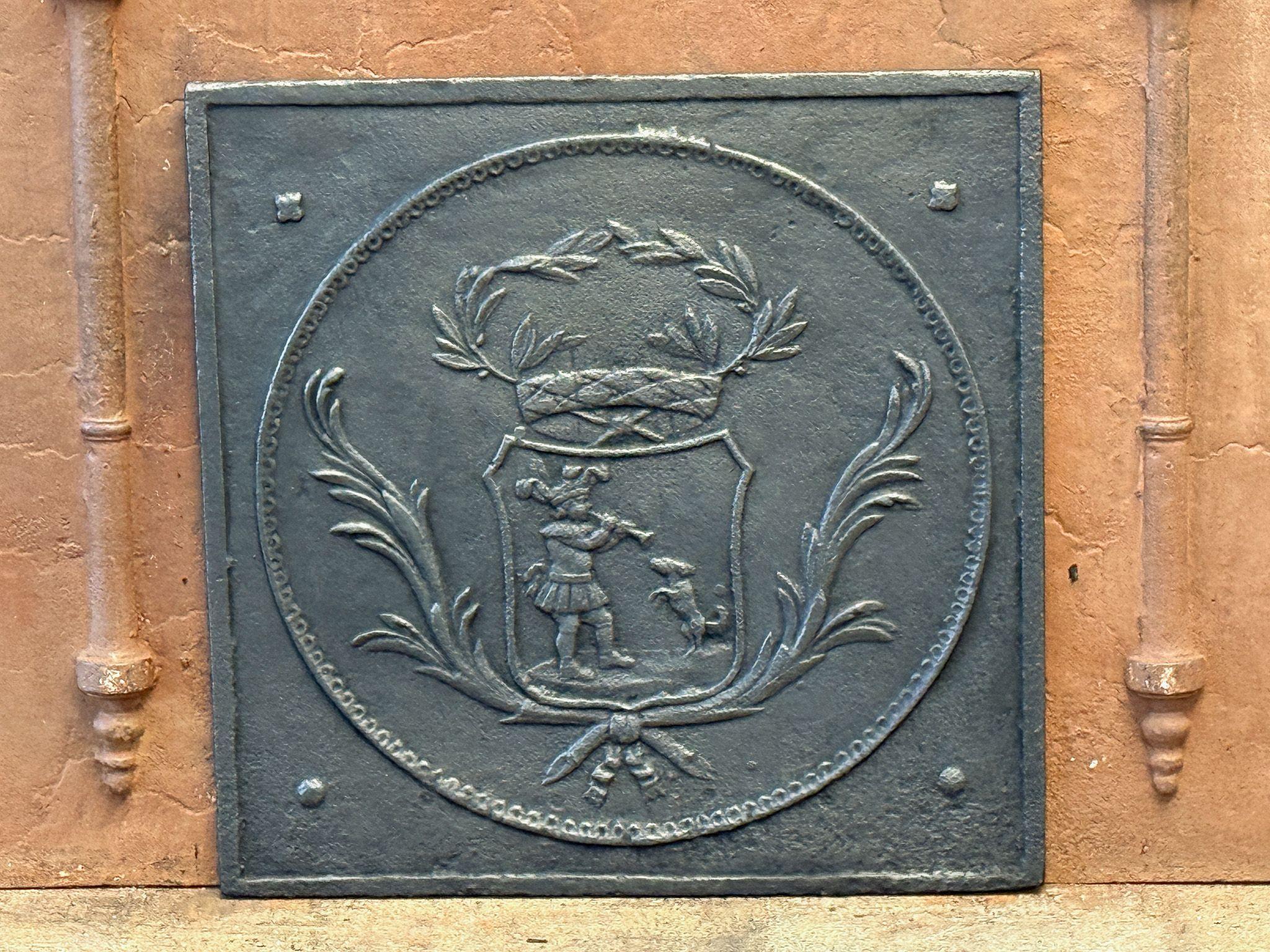 XVIIIe - XIXe siècle Plaque de cheminée française d'époque Napoléon III avec un joueur de cornemuse et son chien dansant. 

La plaque de cheminée est en fonte et de couleur noir/étain. Il est en bon état et ne présente pas de fissures.