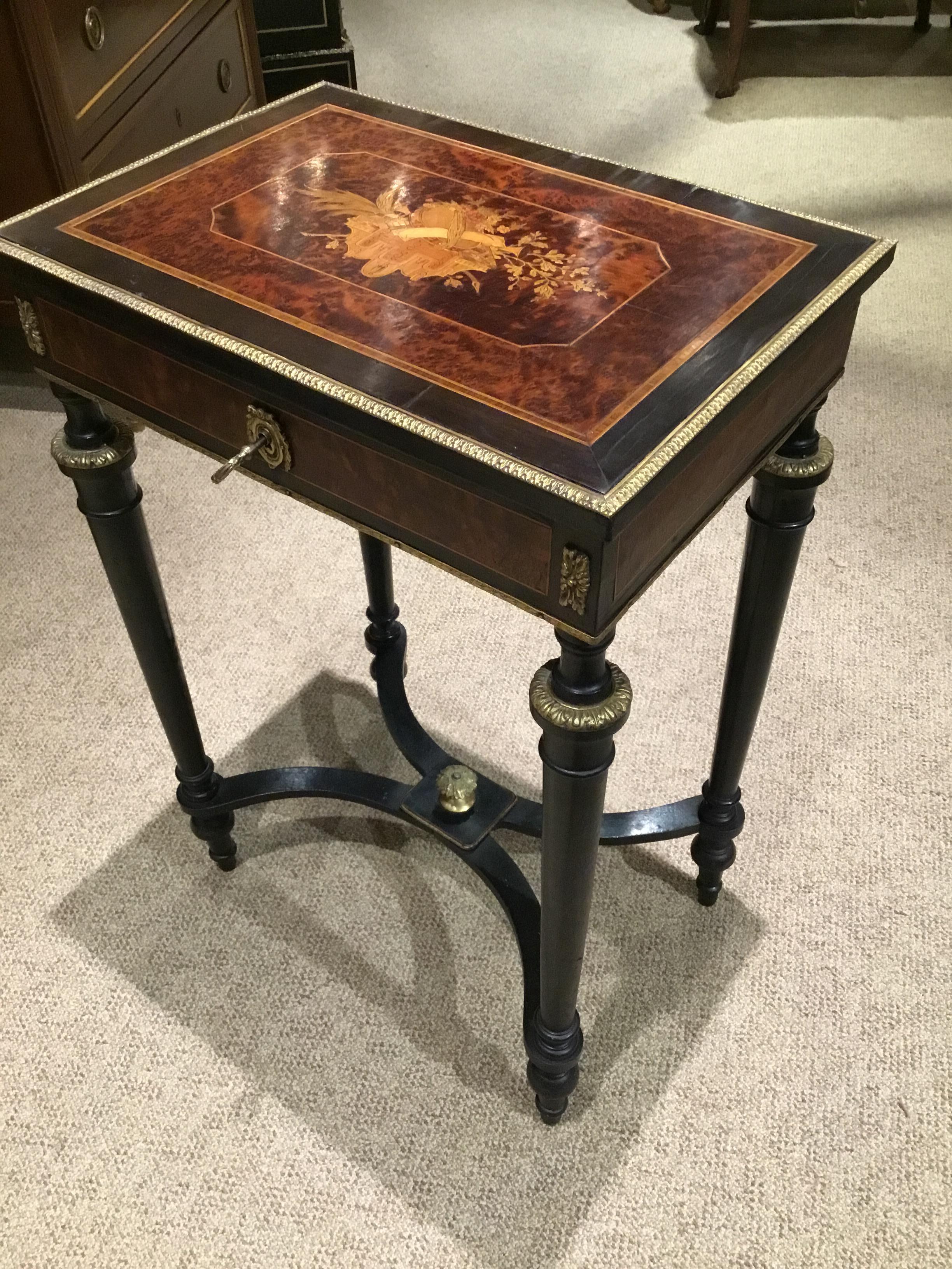 French Napoleon III period vanity table, ebonized frame accented with
Burlwood panels, hinged top with marquetry musical instruments,
Oak branches, and floral blooms, reverse with mirror plate and divided
Interior, rising on tapered legs, joined