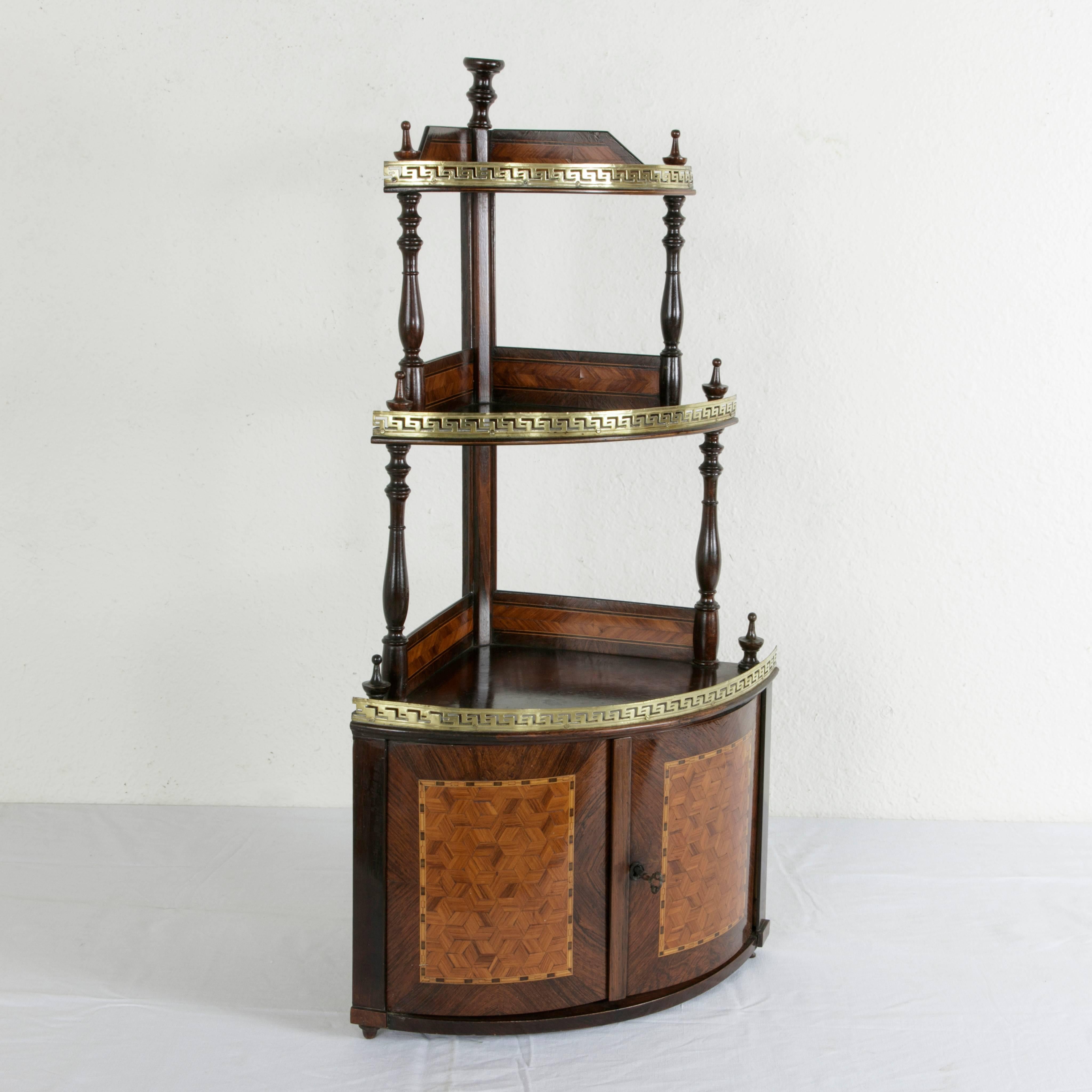 This mid-19th century French Napoleon III period marquetry corner display cabinet features a fine geometric inlay of rosewood and lemon wood inset in a palisander field. Each of the three tiers of the piece is trimmed with a pierced bronze gallery