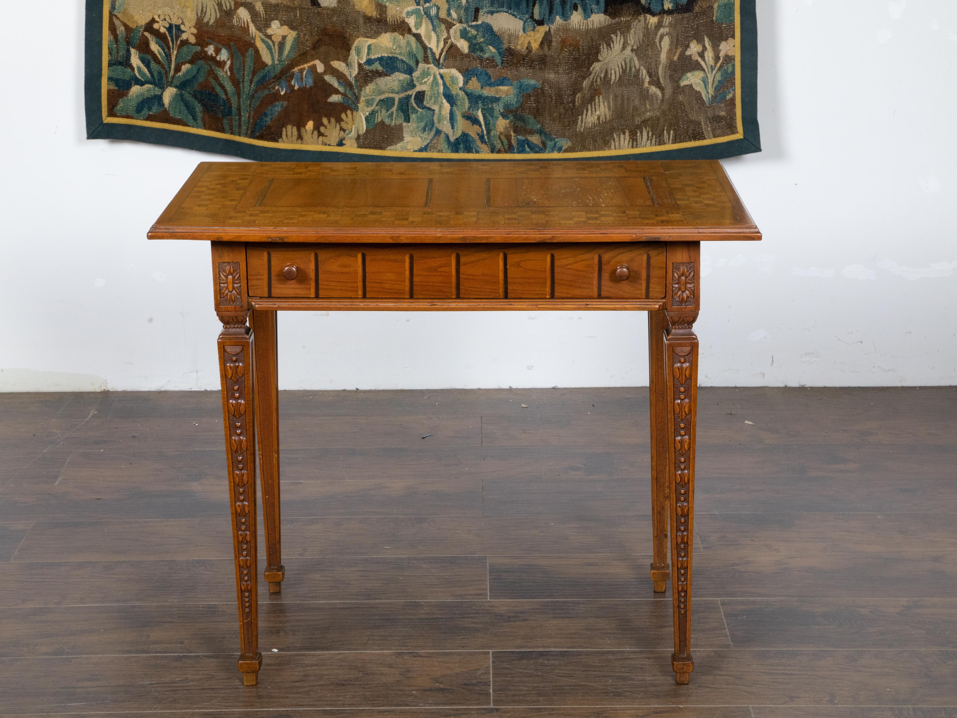 A French Napoléon III period walnut side table from the Mid 19th Century, with inlaid parquetry top, single drawer and carved tapering legs. Created during the reign of France's last Emperor Napoléon III, this walnut table captures our attention
