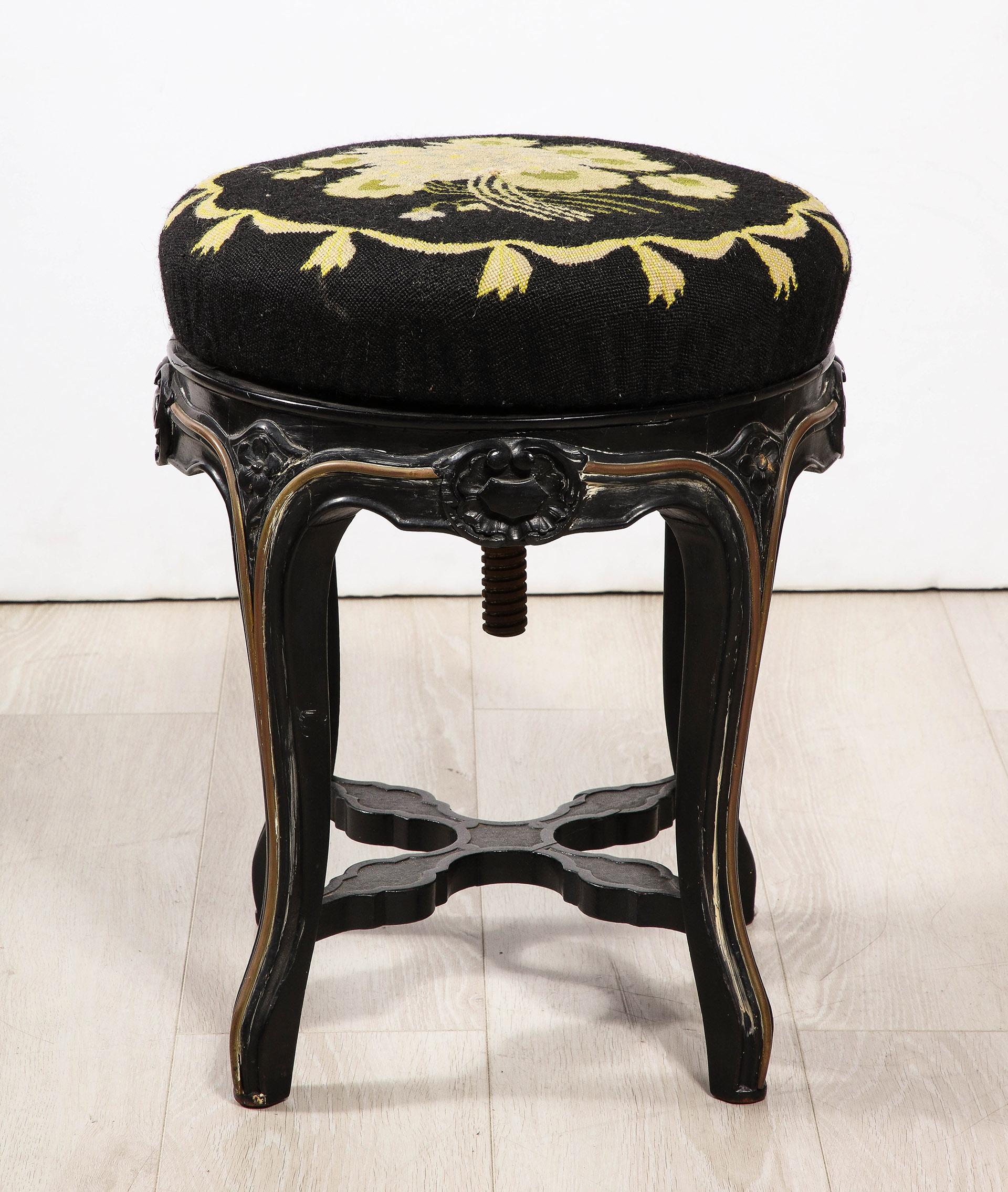 Having an early needle point upholstered seat which can be turned to adjust height. The elegantly carved frame with an ebonized and gilded finish.