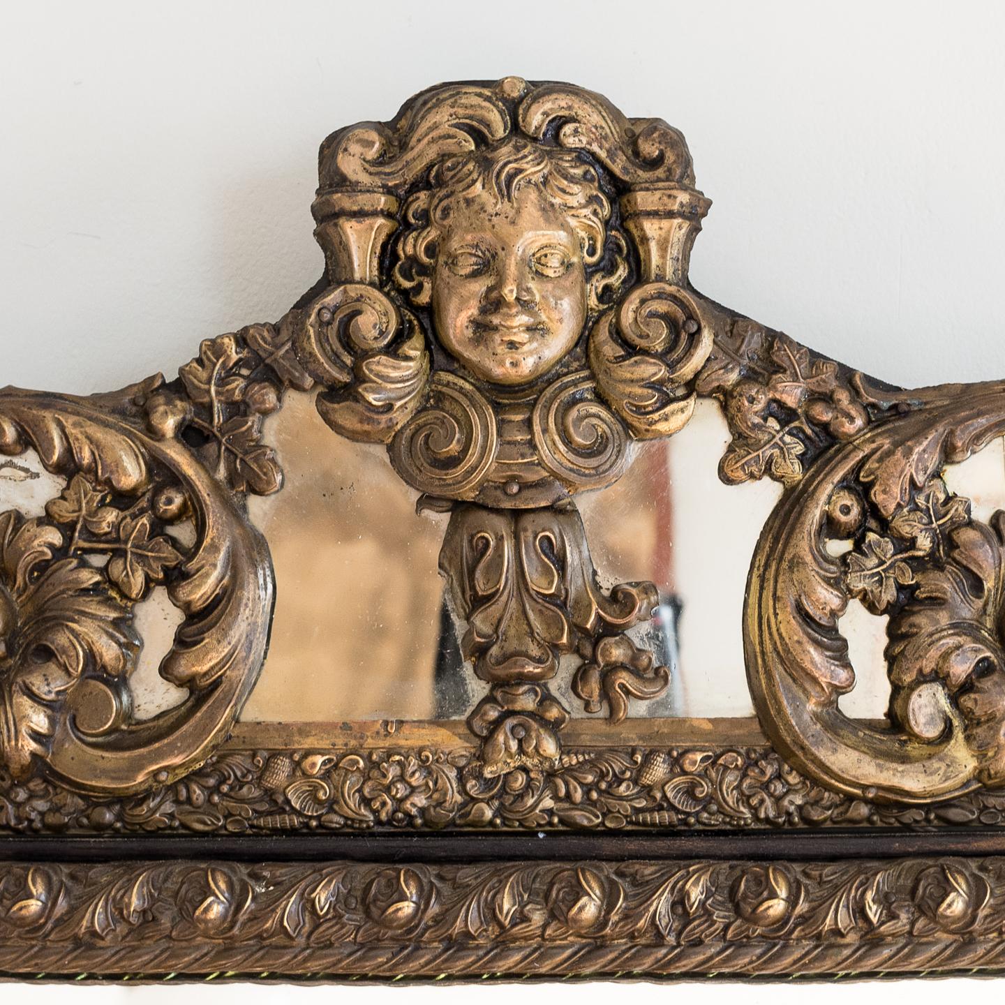 A Napoleon III repoussé cushion mirror, the cresting of scrolled acanthus and cherub mask in the Baroque manner, circa 1860, French.