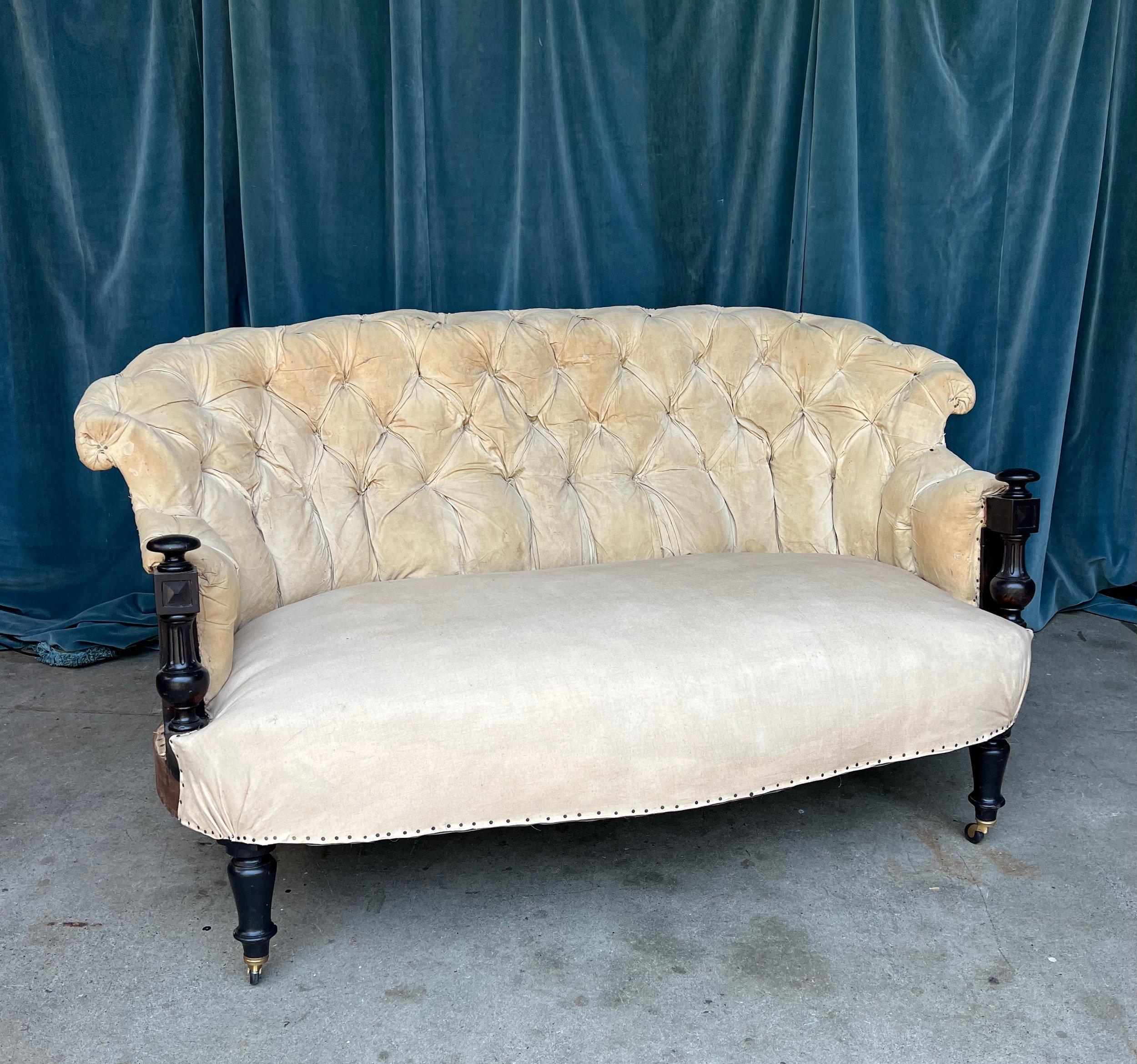 An unusual French 19th Century Napoleon III Tufted Sofa with ebonized arms. This stunning small scale Napoleon III sofa is a true testament to the elegance and craftsmanship of the era. The heavily tufted back is not only visually striking, but also
