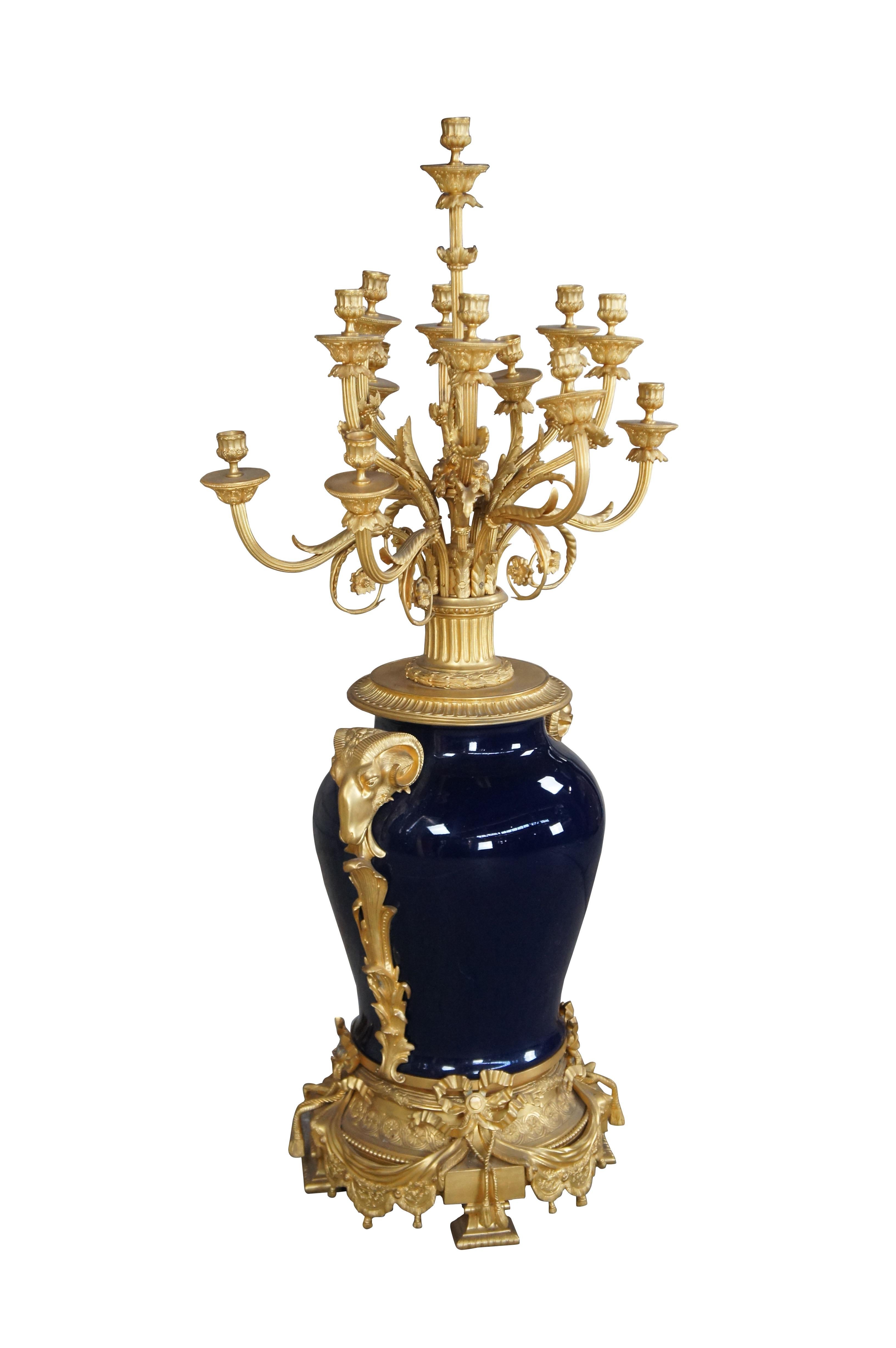 Un elaborato vaso monumentale francese in stile Luigi XVI / Napoleone III Sèvres e un candelabro di Eric Stepniewski. Presenta un'urna di porcellana blu cobalto avvolta da un fogliame in ottone dorato 24k cesellato a basso rilievo con arieti