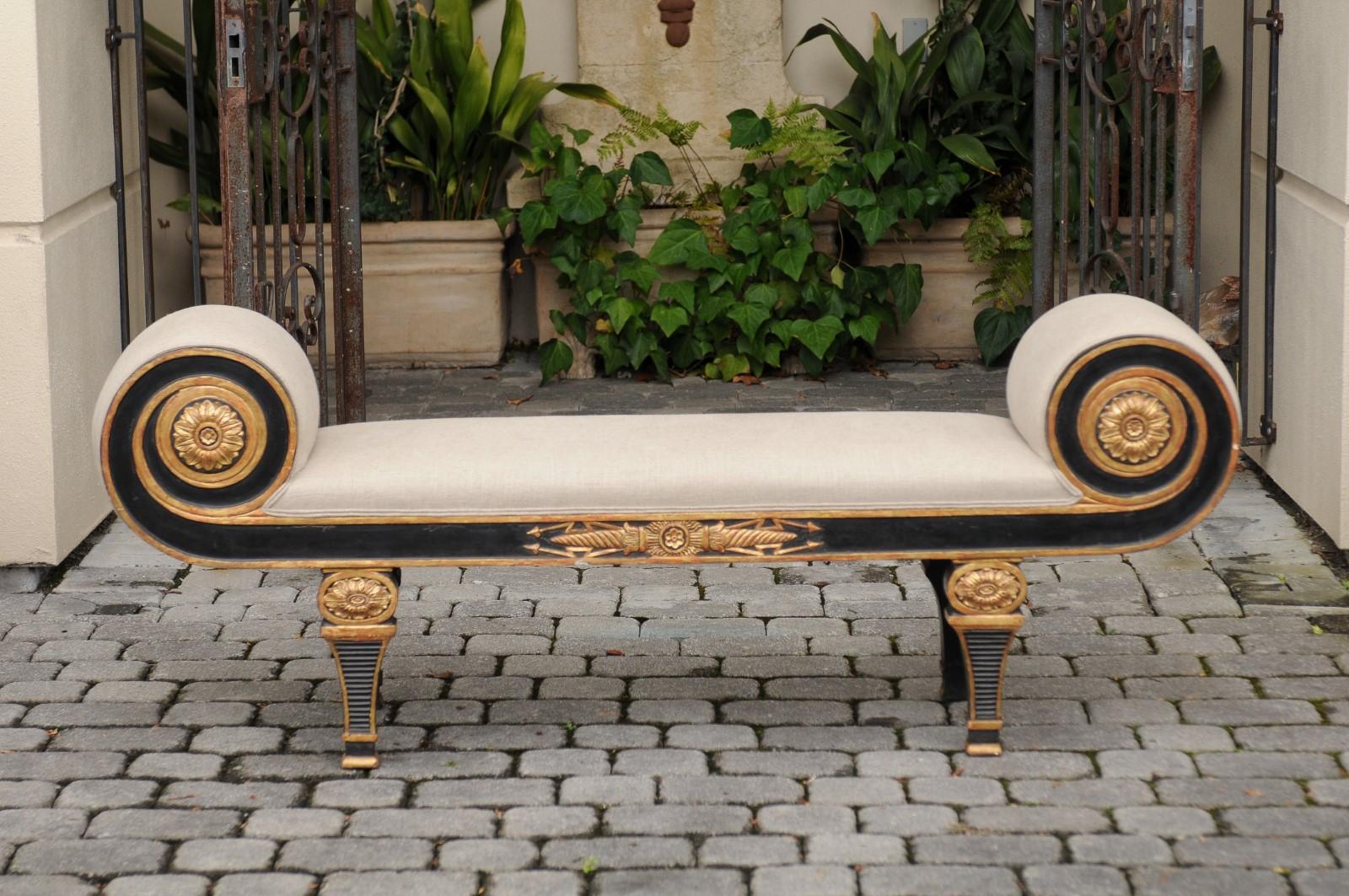 A French Napoleon III style ebonized wood bench from the early 20th century, with scrolled supports, gilded accents and new upholstery. This French bench features an exquisite ebonized silhouette, adorned with eye-catching scrolling supports, each