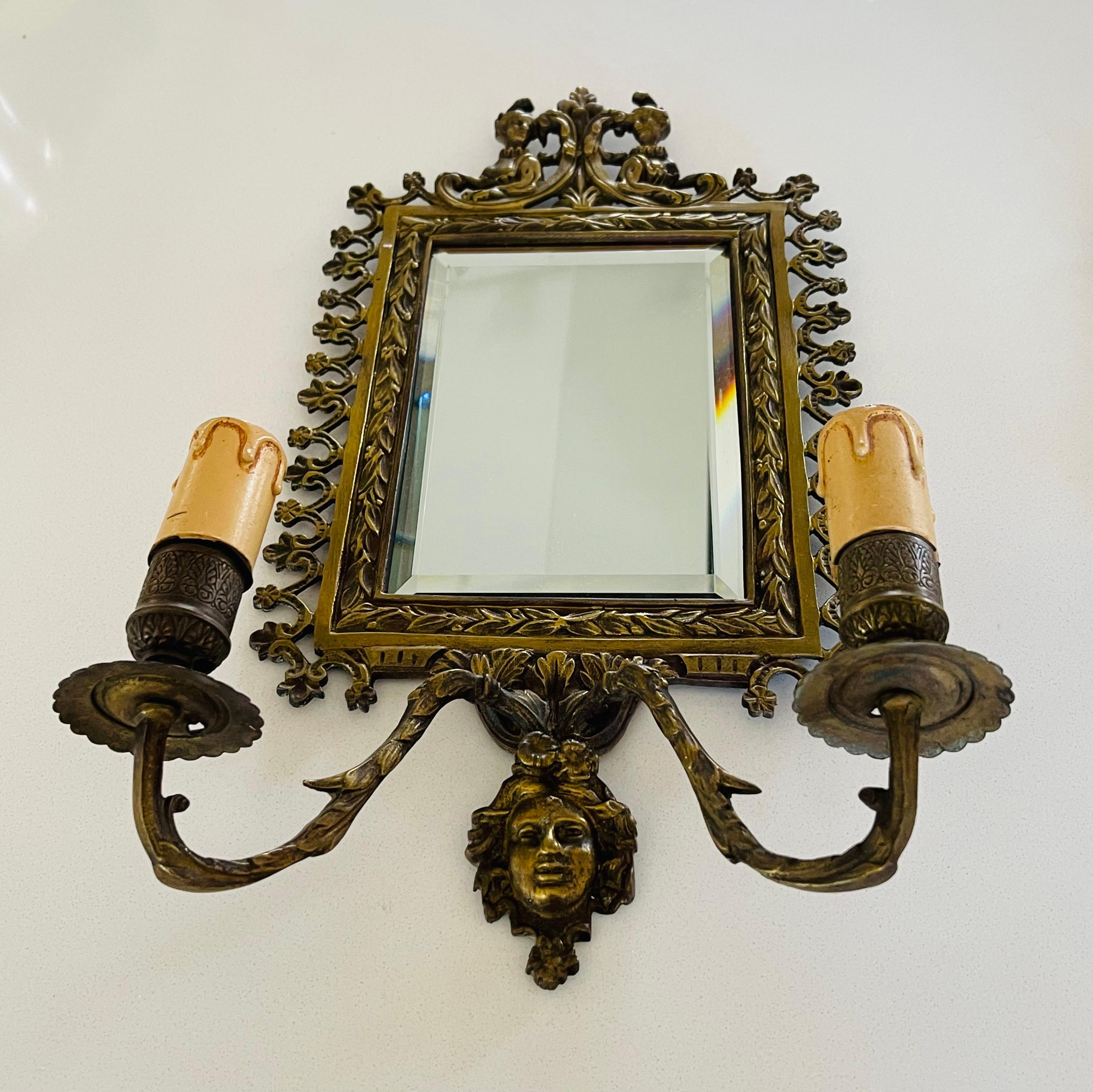 Coppia di appliques in bronzo in stile Napoleone III. Specchio smussato, due rami di luci. Il bronzo è lavorato e decorato con due donne nella parte superiore della cornice e un volto nella parte inferiore.