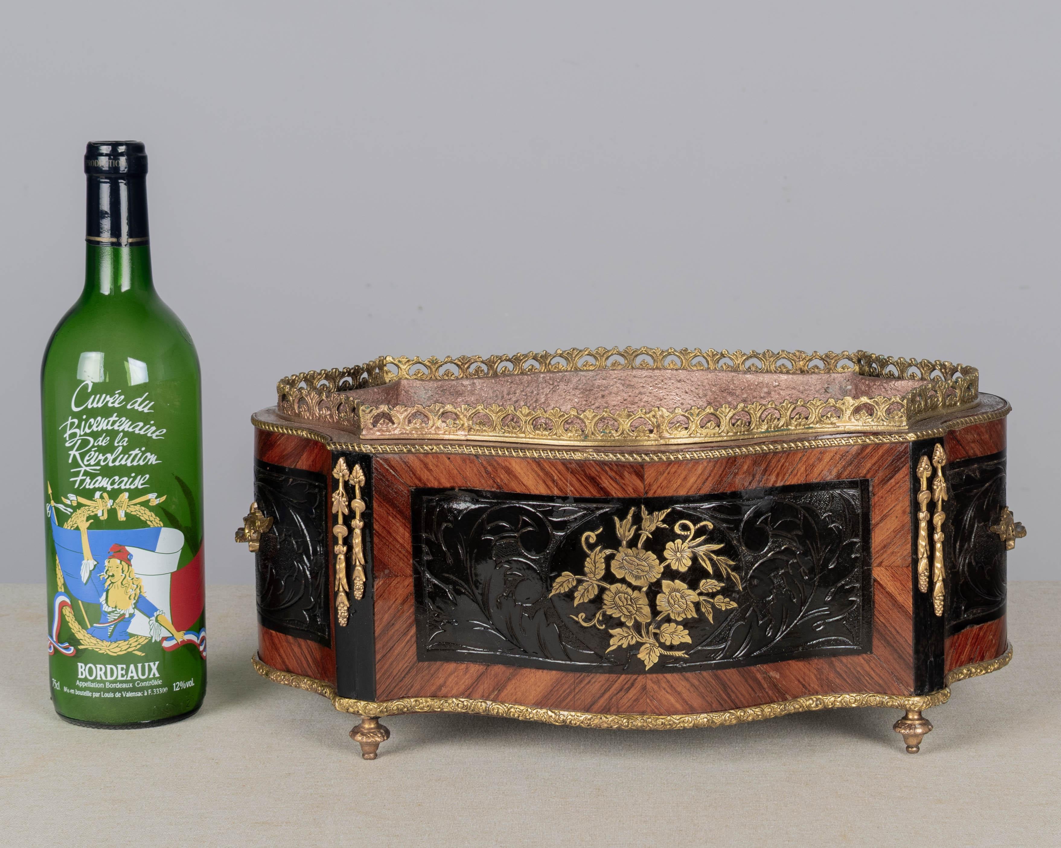 Jardinera o cacharrería francesa de marquetería estilo Napoleón III, de principios del siglo XX, hecha con chapas de caoba con paneles ebonizados y decoración floral de latón incrustado. Asas, galería y embellecedores de bronce fundido. El