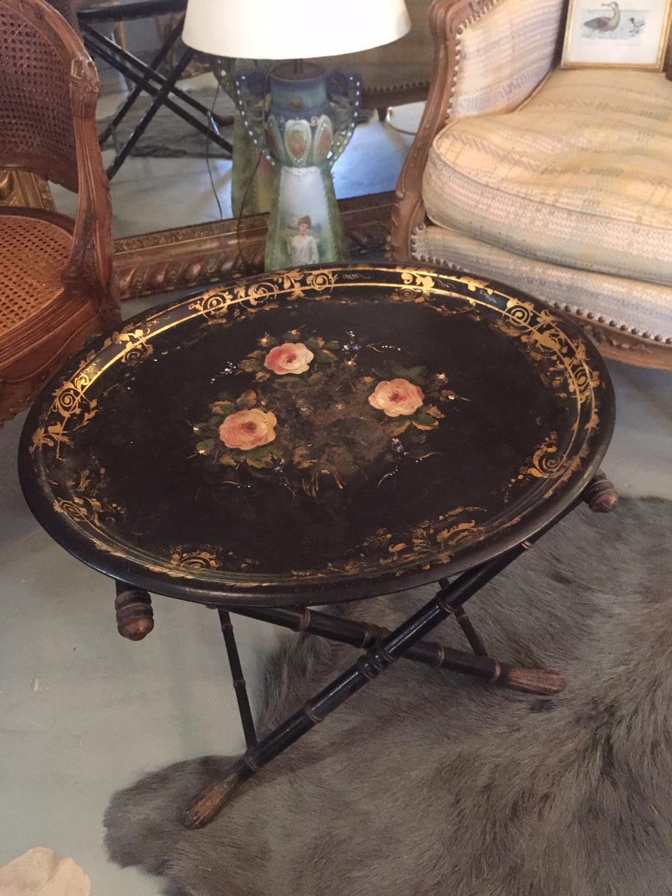 French Napoleon III period tray with his wooden tripod. The tray is black with golden drawing and flowers in the middle which are a little erased.
The tripod can be folded and there is a fabric top to hold the tray.