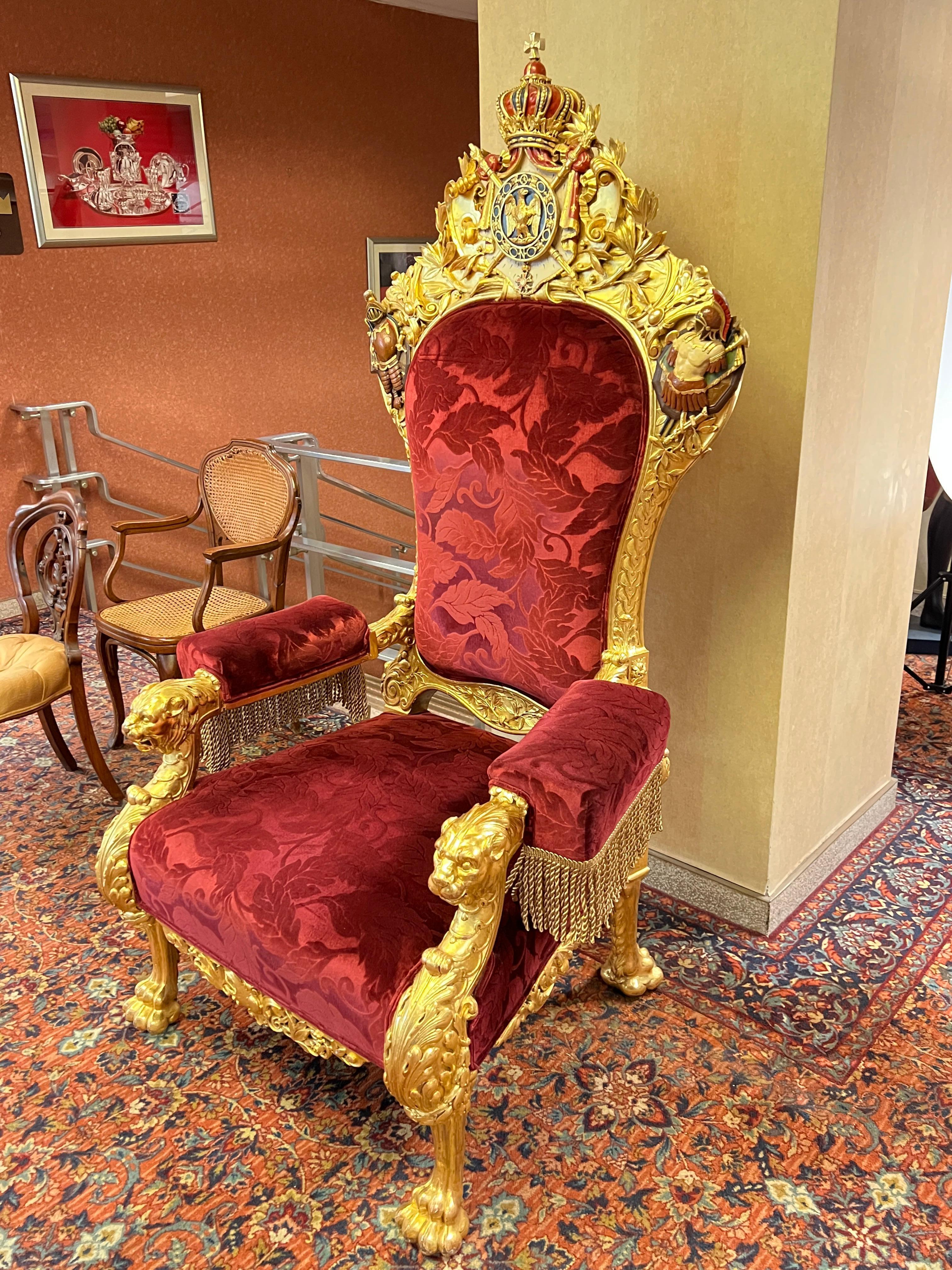 Monumental Napoleonic throne armchair, finely carved with polychrome and gilt surfaces throughout with large coat of arms of the Napoleonic Second Empire (1852-70) on the crest rail, and fine modern burgundy red upholstery.  72 by 38 by 32.5 inches.