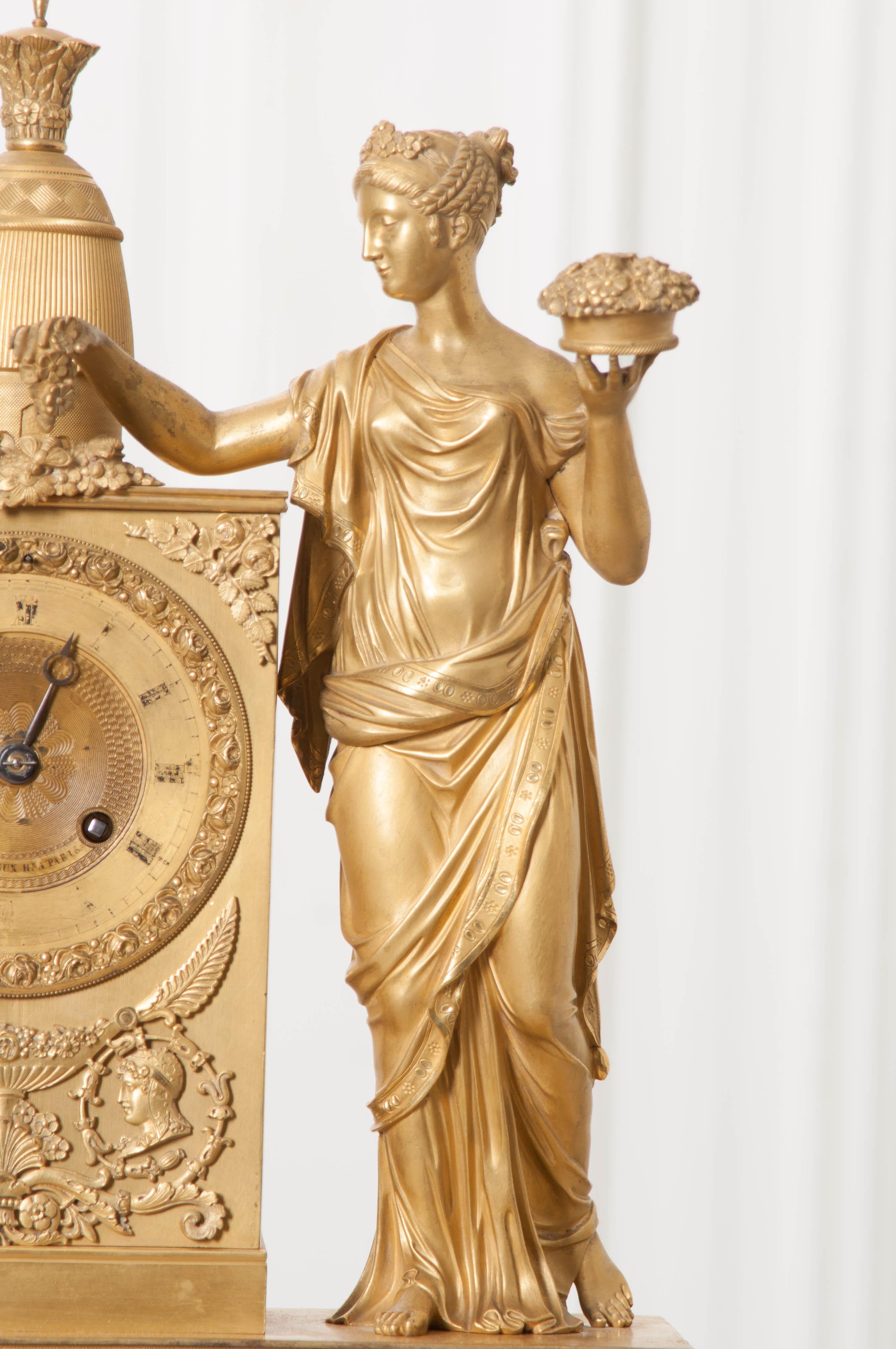 This stunningly-detailed period Napoleonic Empire fire-gilded bronze mantel clock, by Victor Cacheux, Paris, circa 1820, features a figure of Josephine, also known as the Patroness of Roses, in neoclassical dress with a basket of flowers and a