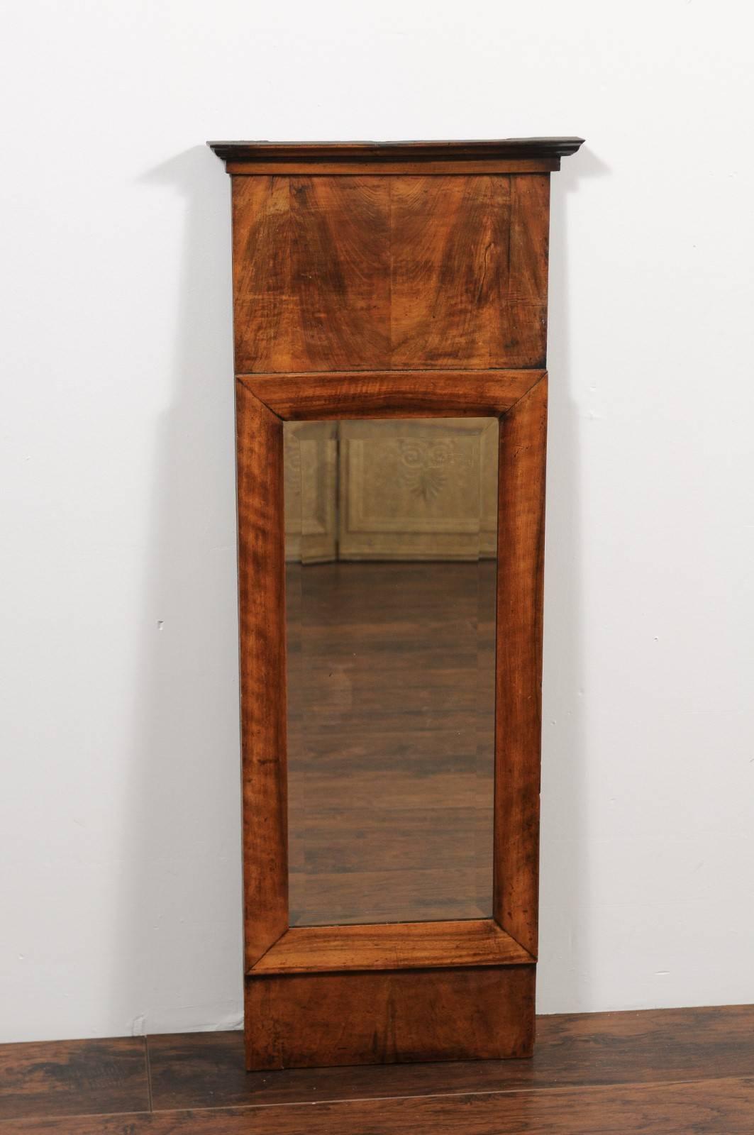 A narrow French walnut veneered mirror from the second half of the 19th century with beveled mirror plate. This French walnut bookmarked-veneer mirror was born in the 1870s, in the later years of the reign of Emperor Napoleon III reign. Featuring a