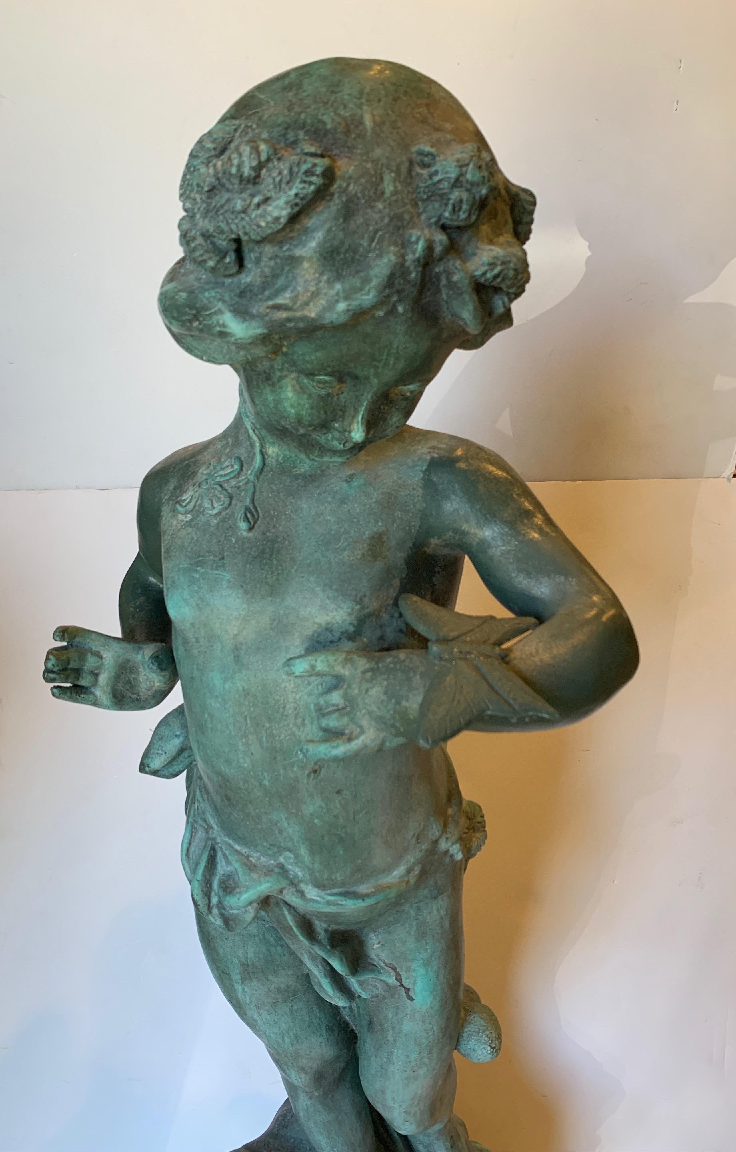 Natural patina lead figure. Girl with a resting butterfly on her arm, early 20th century. Outdoor garden statue.