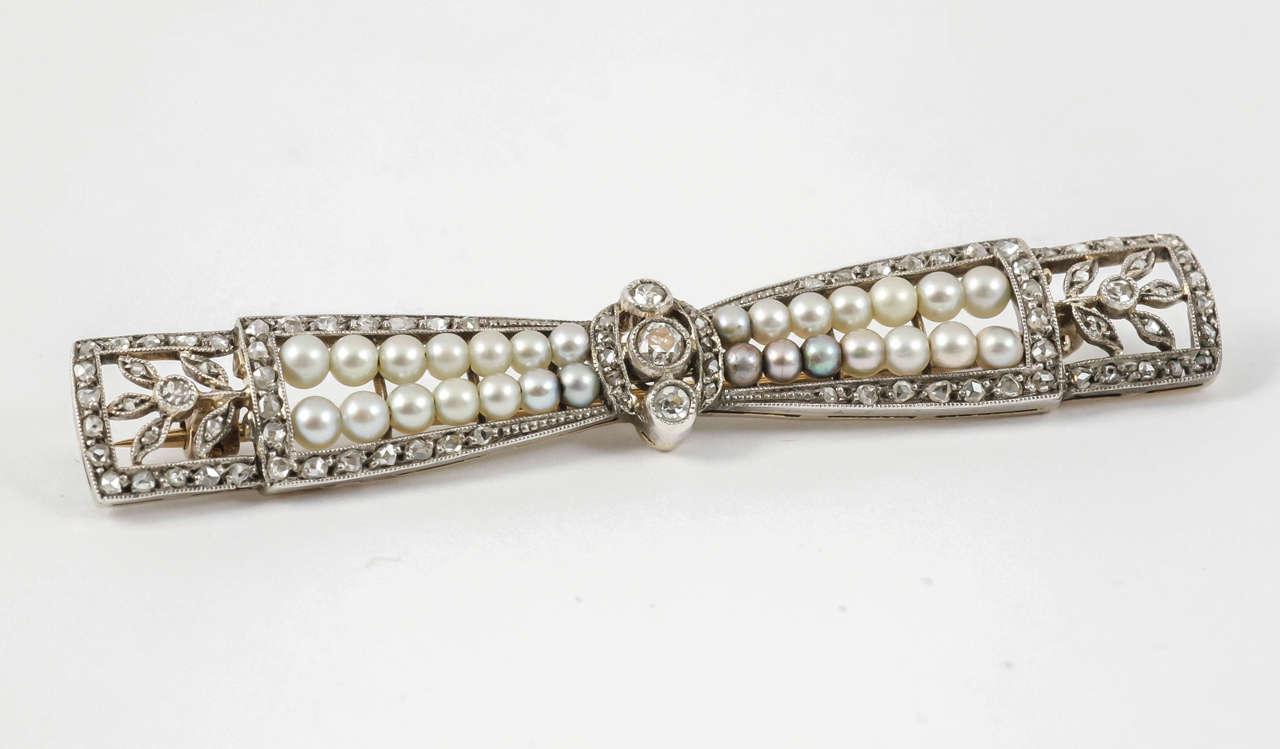 A finely made platinum mounted bow brooch set with rose cut diamonds and natural pearls strung on wire. The centre set with three brilliant cut diamonds. French marks.
Measures 57mm in length x 8mm in height.
Antique piece (over 100 years