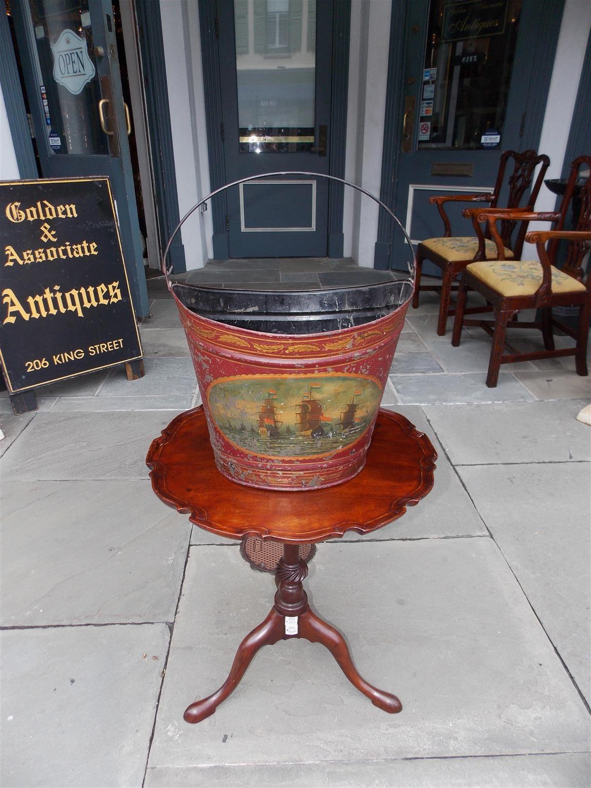 French Navette form tole fuel bucket with foliage motif, oval nautical scenes, and the original mounted iron handle, Early 19th century.